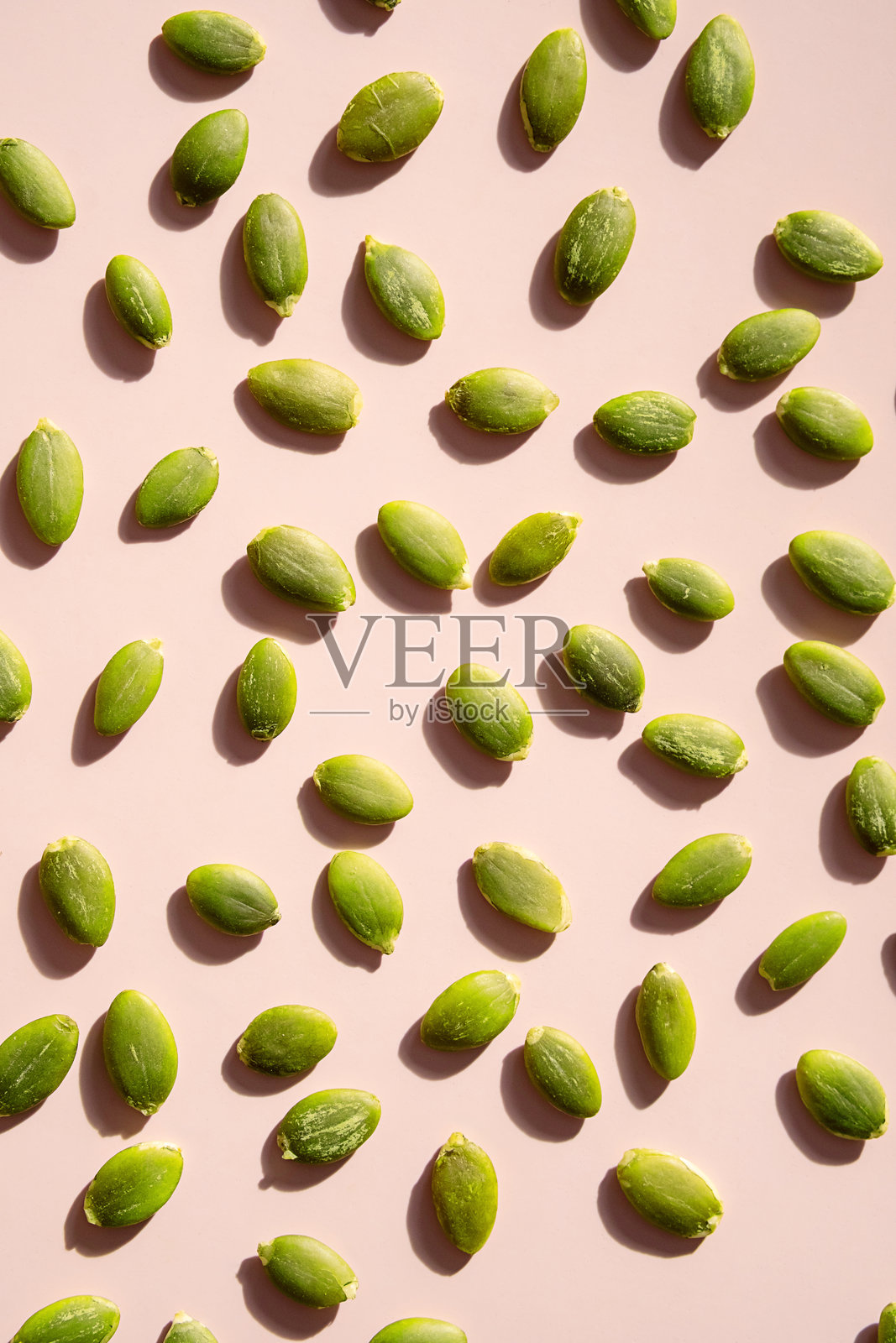 粉色表面上的去皮南瓜籽。照片摄影图片