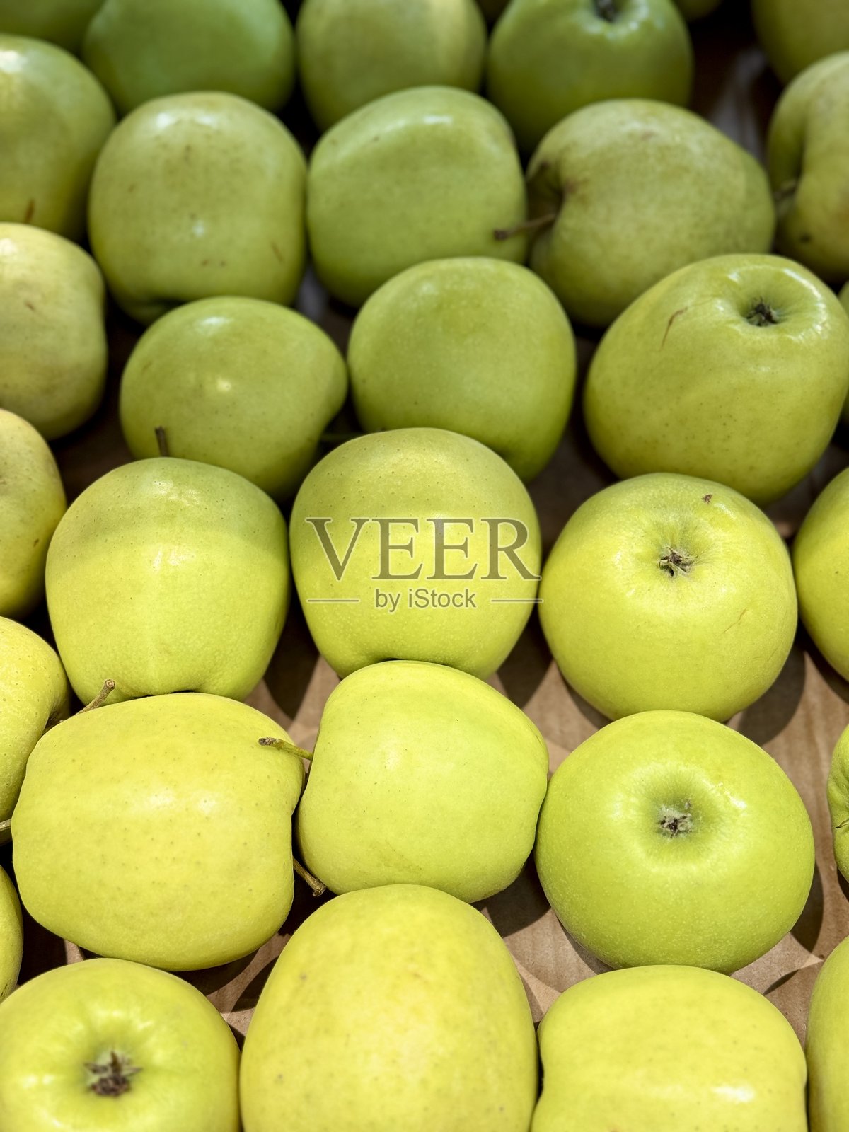 在热闹的市场环境中，鲜艳多彩的新鲜脆绿苹果整齐地摆放着。特写镜头。照片摄影图片