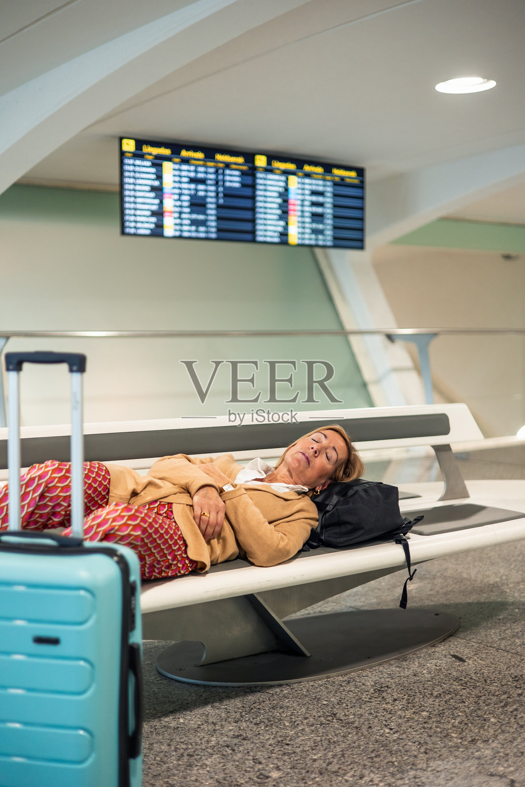 在机场长椅上睡觉的老年女性，等待她的航班照片摄影图片