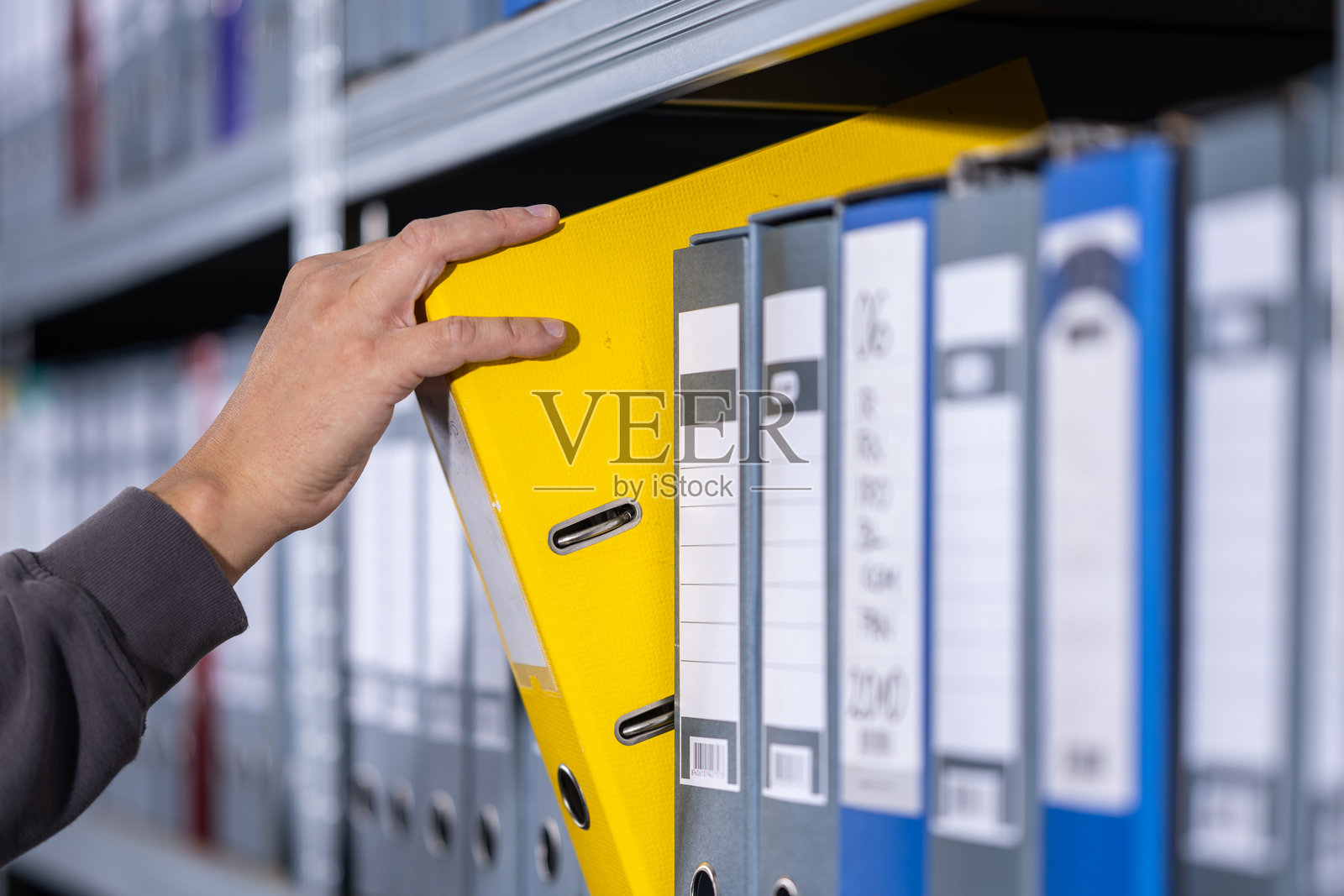 手从整齐的档案架上取出黄色文件夹照片摄影图片