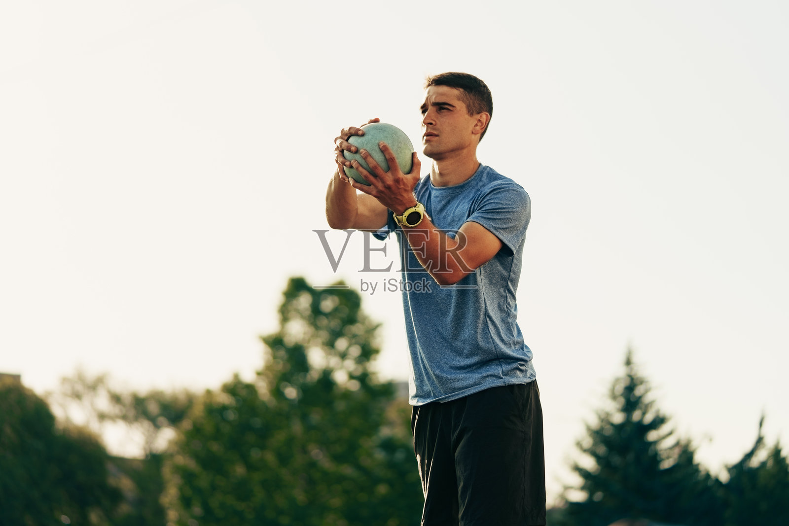 运动员在傍晚的光线下进行户外训练，使用重球练习投掷。照片摄影图片