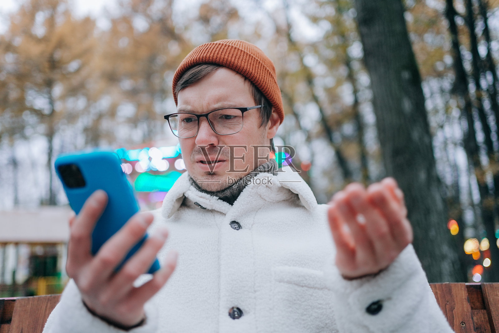 在游乐园里，困惑的男人正在手机上阅读坏消息照片摄影图片