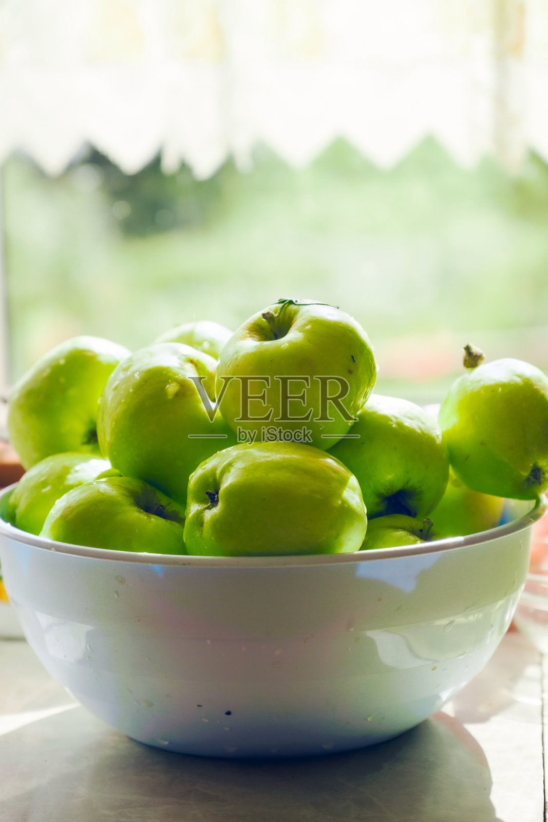 一碗绿色苹果放在一个乡村风格的台面上照片摄影图片