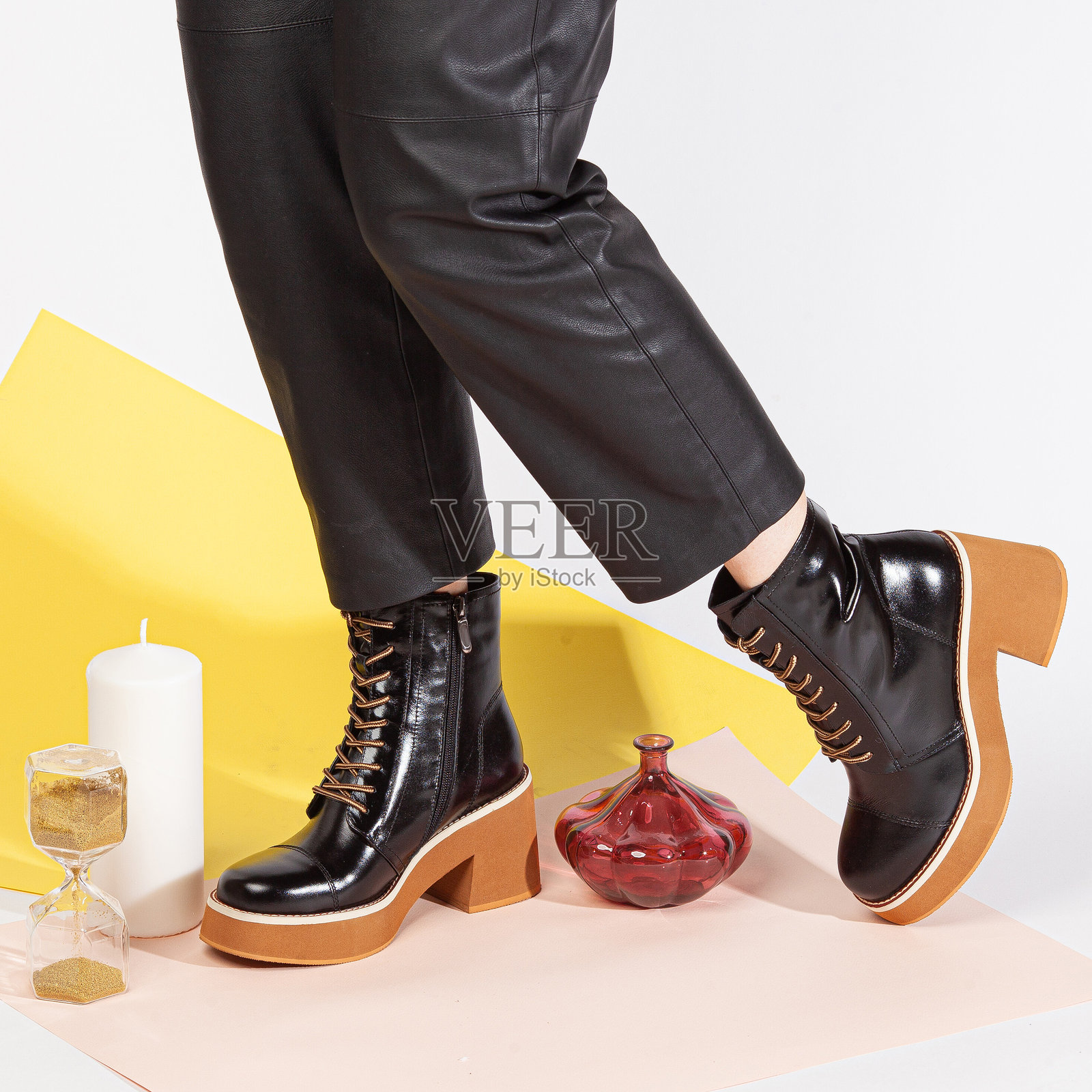 穿着黑色裤子和中跟黑色短鞋的女性双腿在彩色背景前的工作室中站立。照片摄影图片