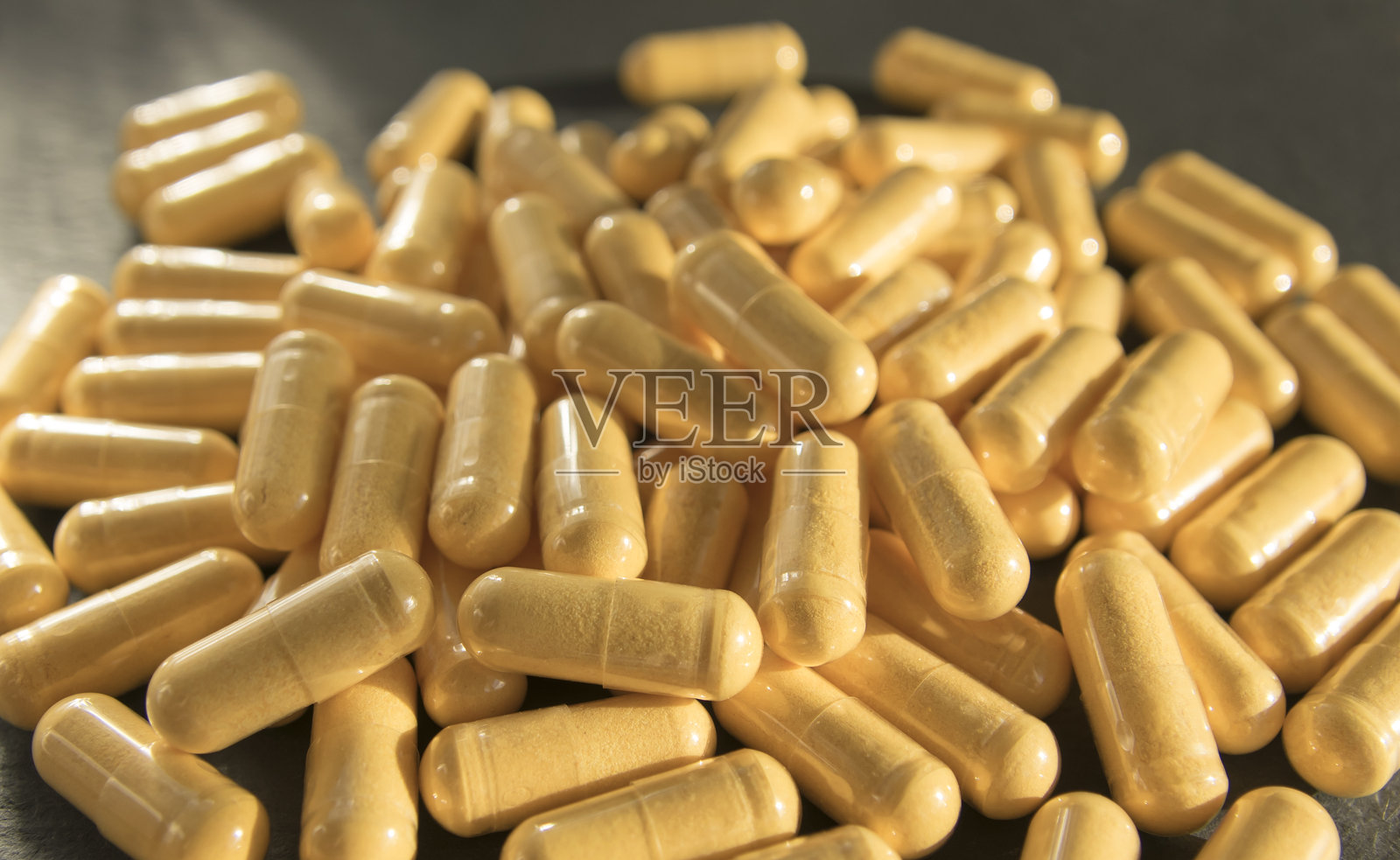 黑色石材背景上的黄色药片或药丸。照片摄影图片