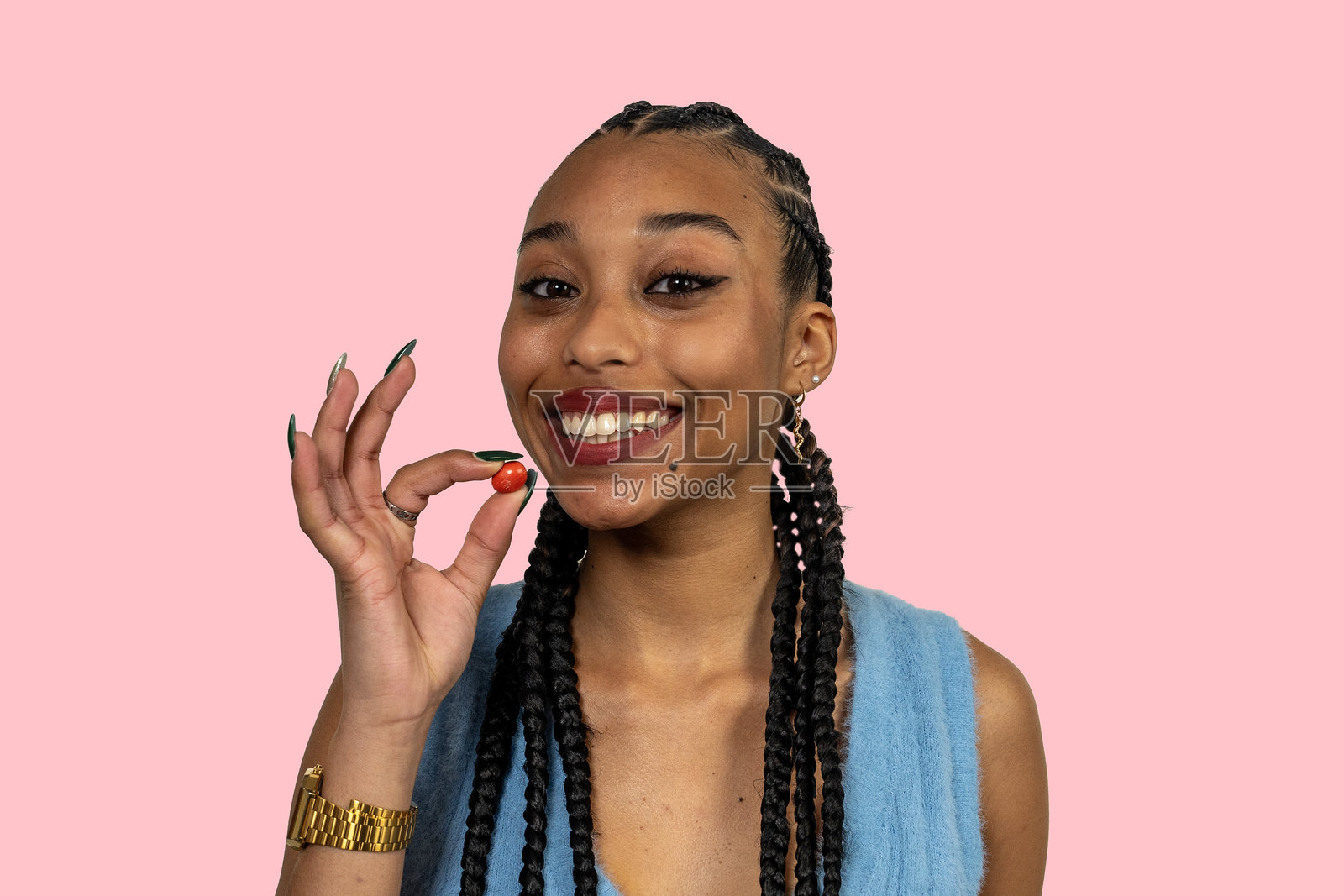 年轻微笑的女性在粉色背景下手持糖果照片摄影图片