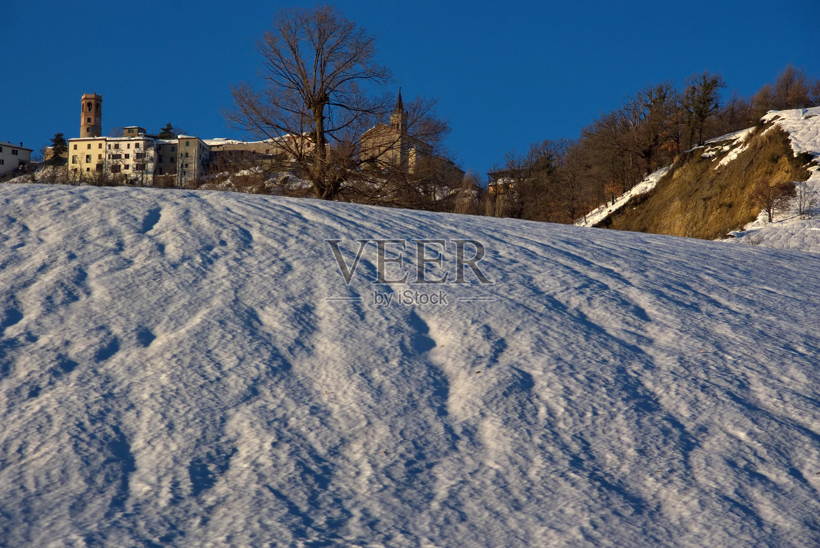 被雪覆盖的田野与山丘上的村庄景观照片摄影图片