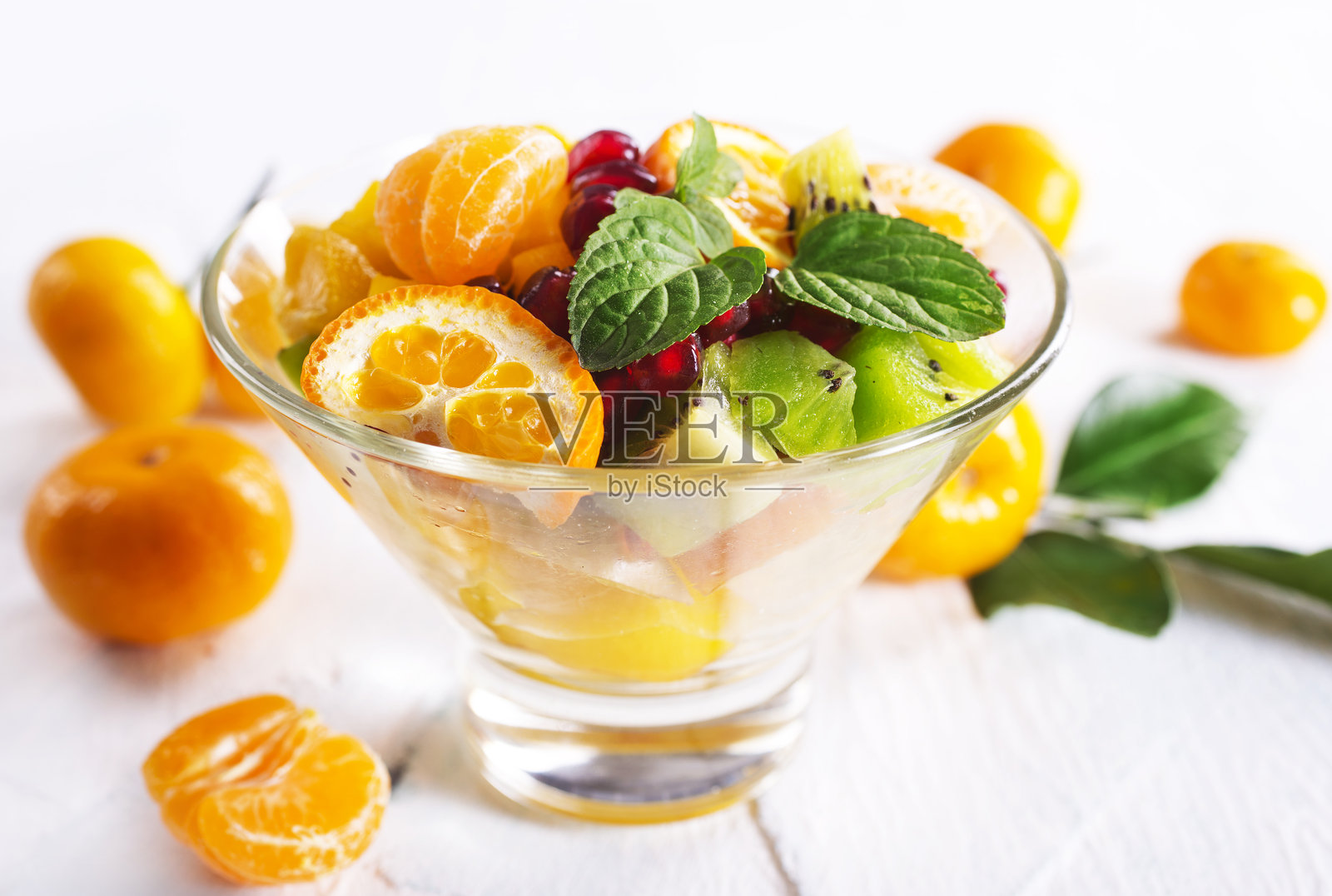 甜美的橘子和绿色的叶子在浅色背景上照片摄影图片