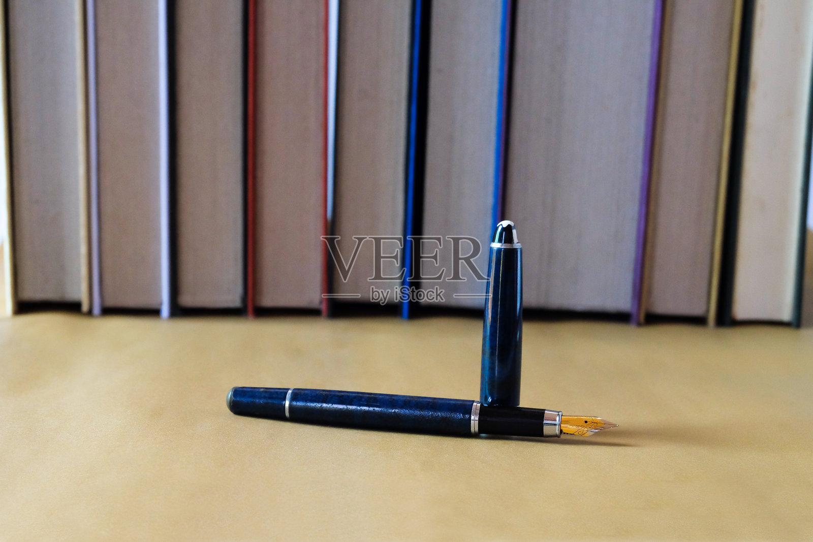 旧钢笔放在桌子上，背景是书籍。照片摄影图片