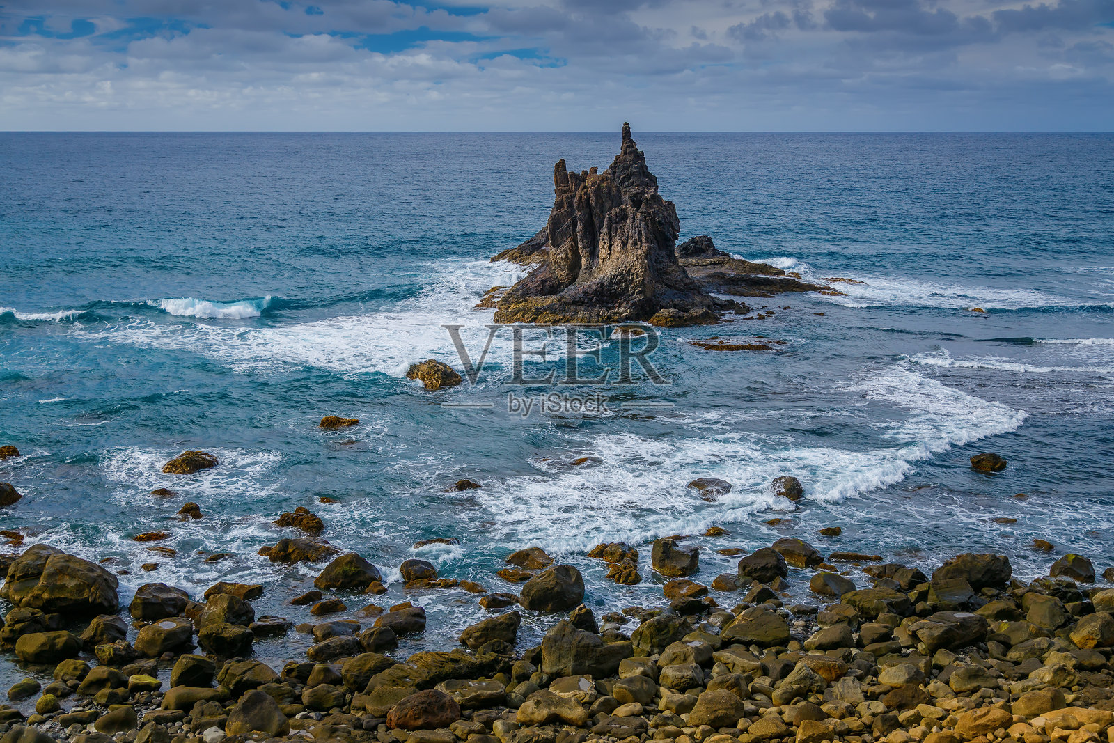 特内里费岛贝尼霍海滩的海岸景观，显著的岩石从海中拔地而起，周围是拍打而来的海浪。照片摄影图片