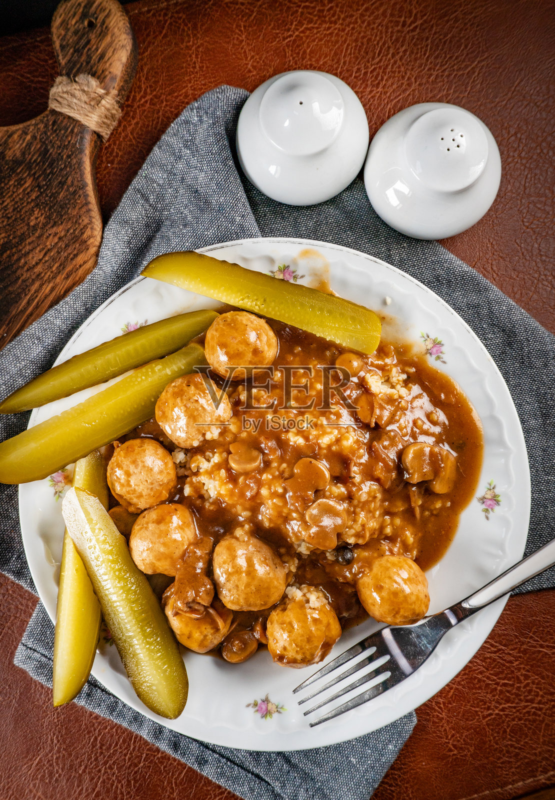 鸡肉丸和蘑菇酱，配以粗麦粉和腌黄瓜。照片摄影图片