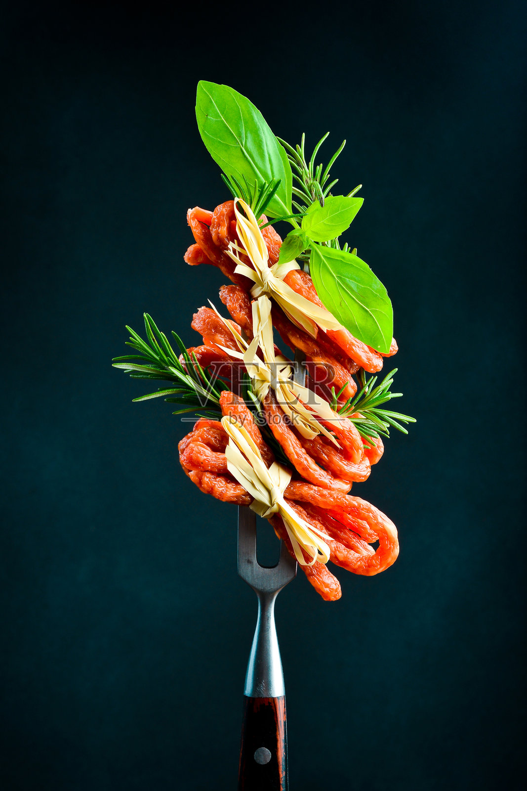 干熏卡巴诺斯或卡巴诺西传统波兰细香肠放在金属叉上。卡巴诺斯特写，背景为黑色。照片摄影图片