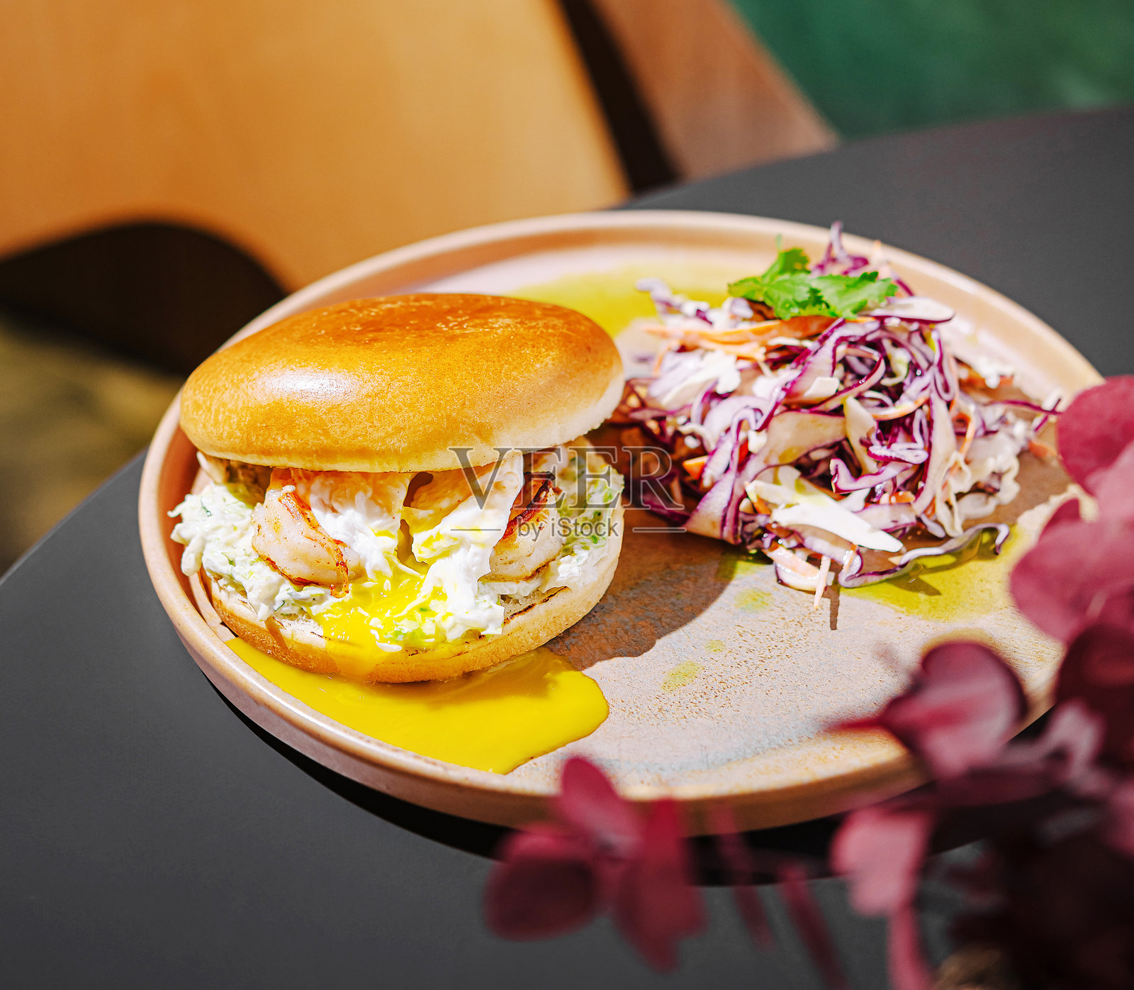 美味的虾汉堡配新鲜的卷心菜沙拉，摆放在温馨餐厅的木桌上照片摄影图片