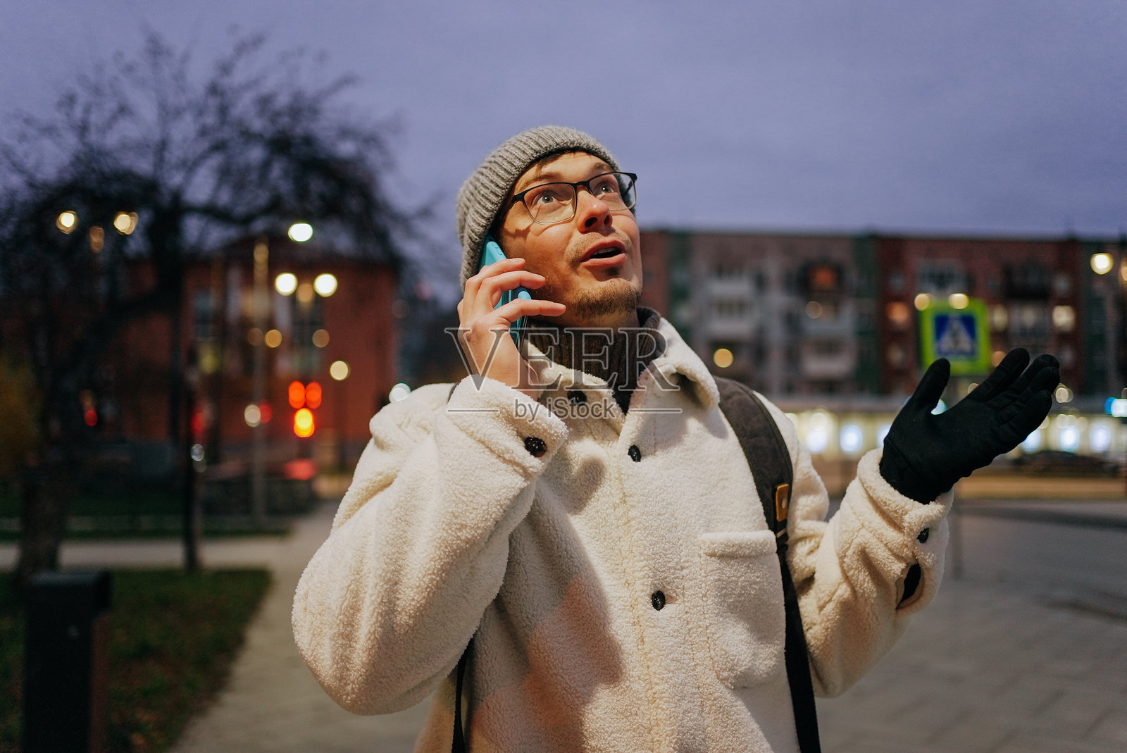 惊讶的男人在城市夜晚用智能手机通话照片摄影图片
