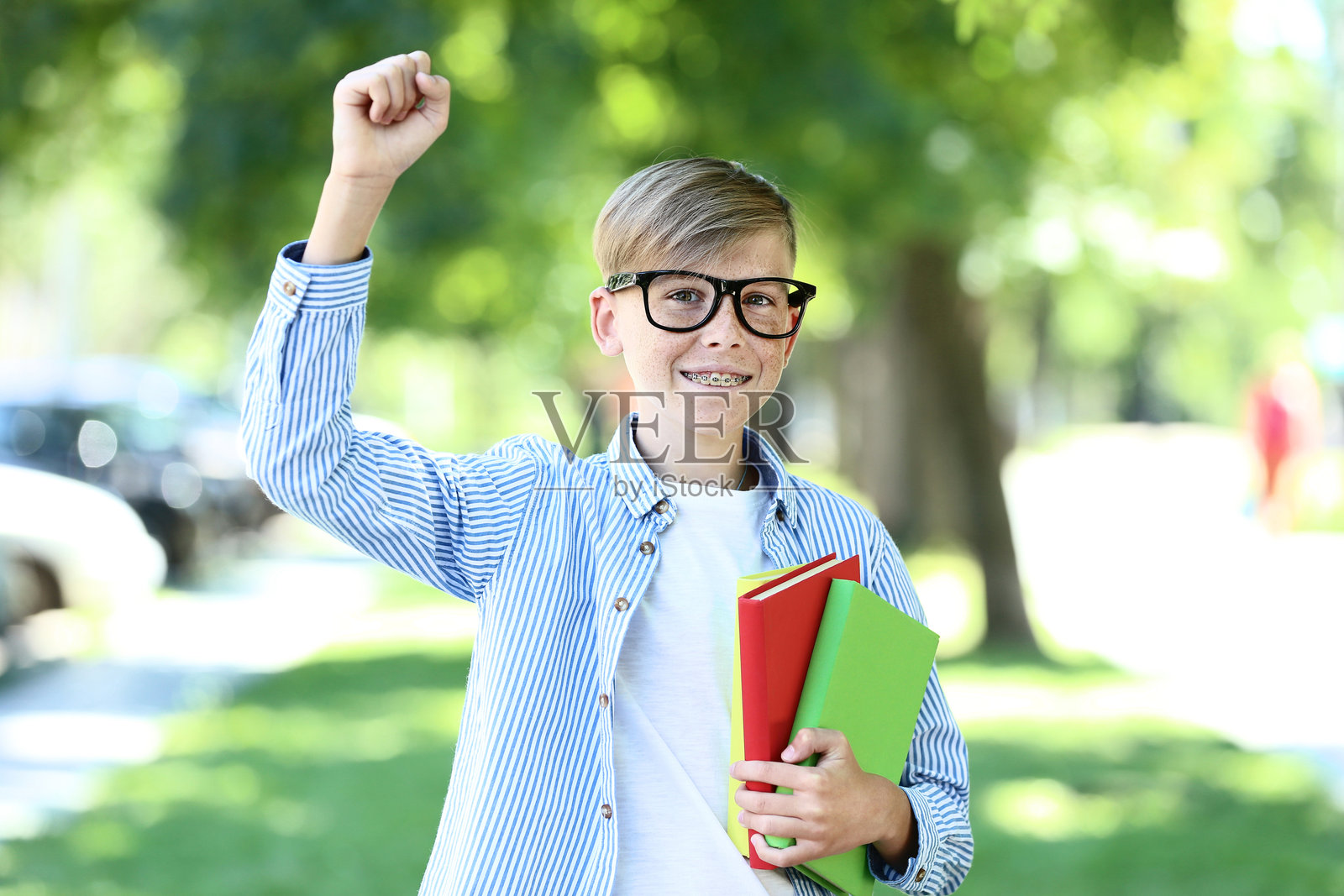 公园里拿着书的小男孩照片摄影图片