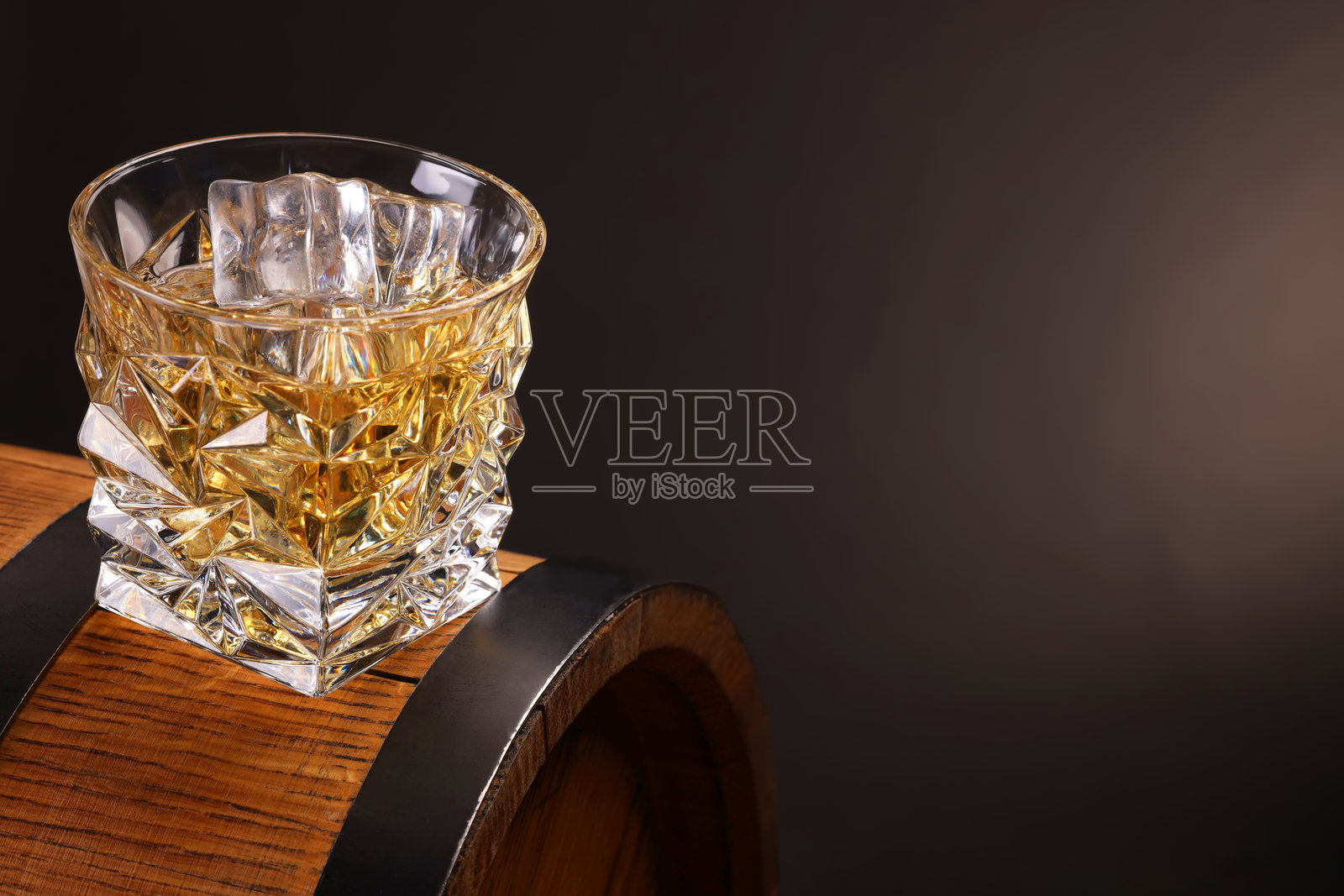 木桶上的玻璃杯威士忌，背景昏暗，留有文字空间照片摄影图片