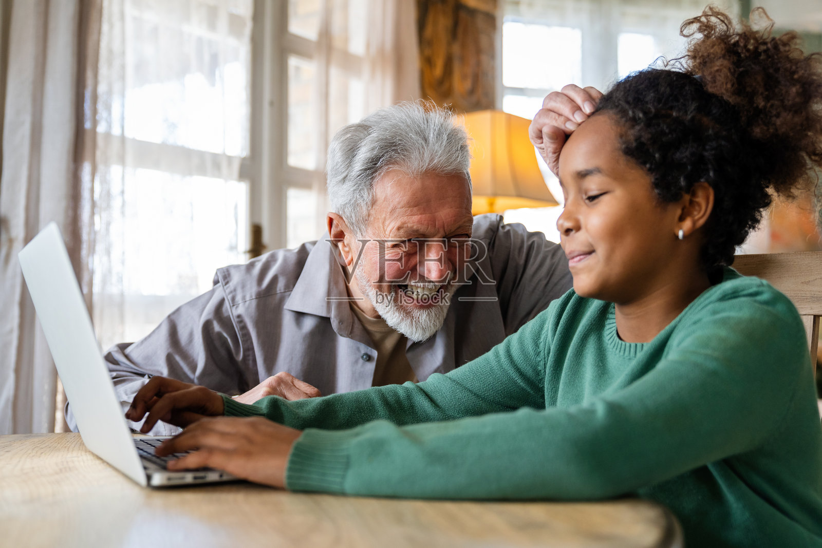 少女与祖父一起使用笔记本电脑进行教育、在线游戏、娱乐和远程学习照片摄影图片