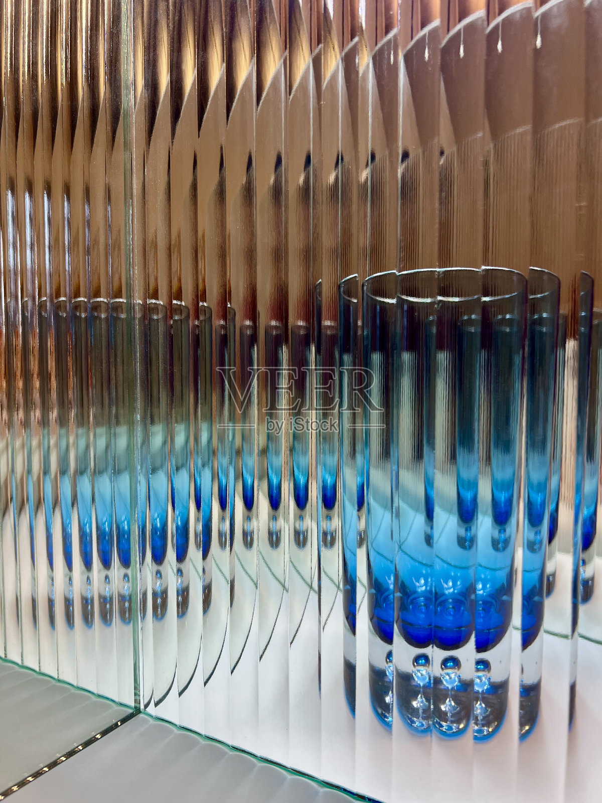 透光的玻璃杯，透过波纹玻璃和镜面墙。照片摄影图片