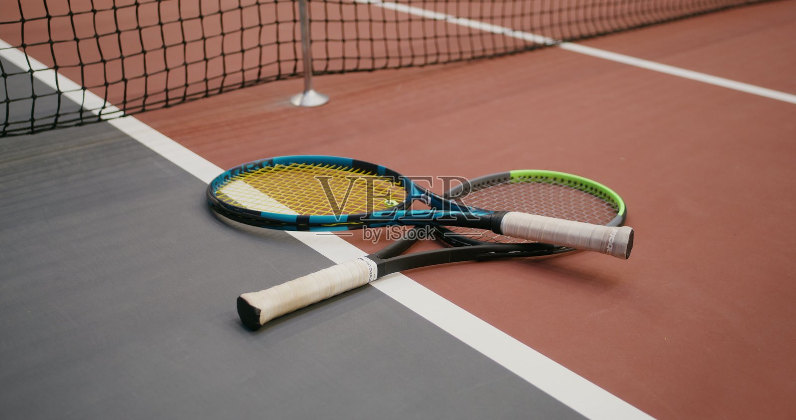 两个网球拍放在靠近球网的地板上。照片摄影图片