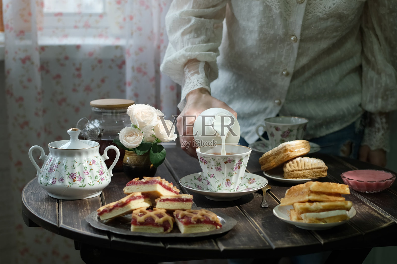英式早餐。一个人在厨房里将牛奶倒入茶杯中。照片摄影图片