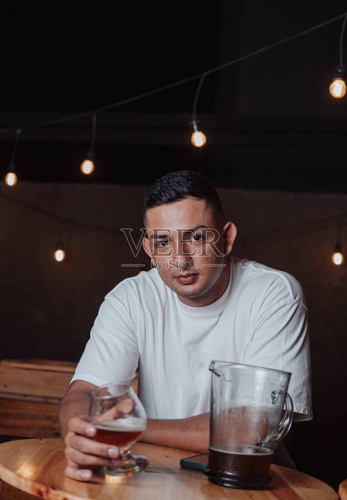拉丁裔男子在夜晚的酒吧里喝啤酒照片摄影图片