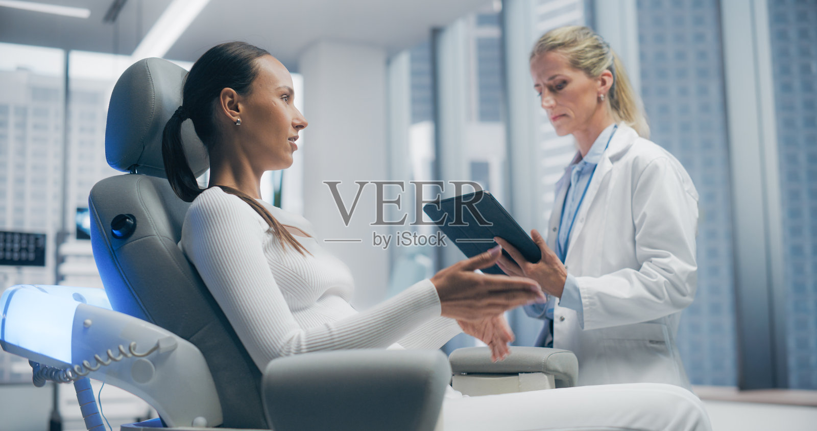 女性医生在未来医疗实验室诊所与女性患者咨询，讨论各种医疗解决方案。现代诊所配备先进技术，拥有高科技医疗环境。照片摄影图片