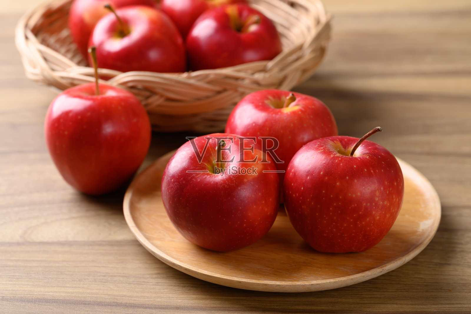 红色苹果（佳乐苹果）放在木质盘子上，背景为木质纹理照片摄影图片