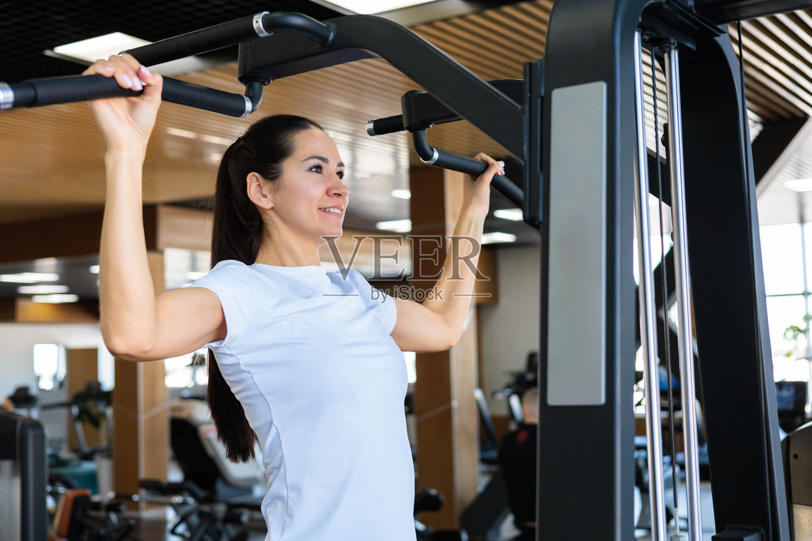 年轻美丽的亚洲女性，身材健美，正在做引体向上。照片摄影图片