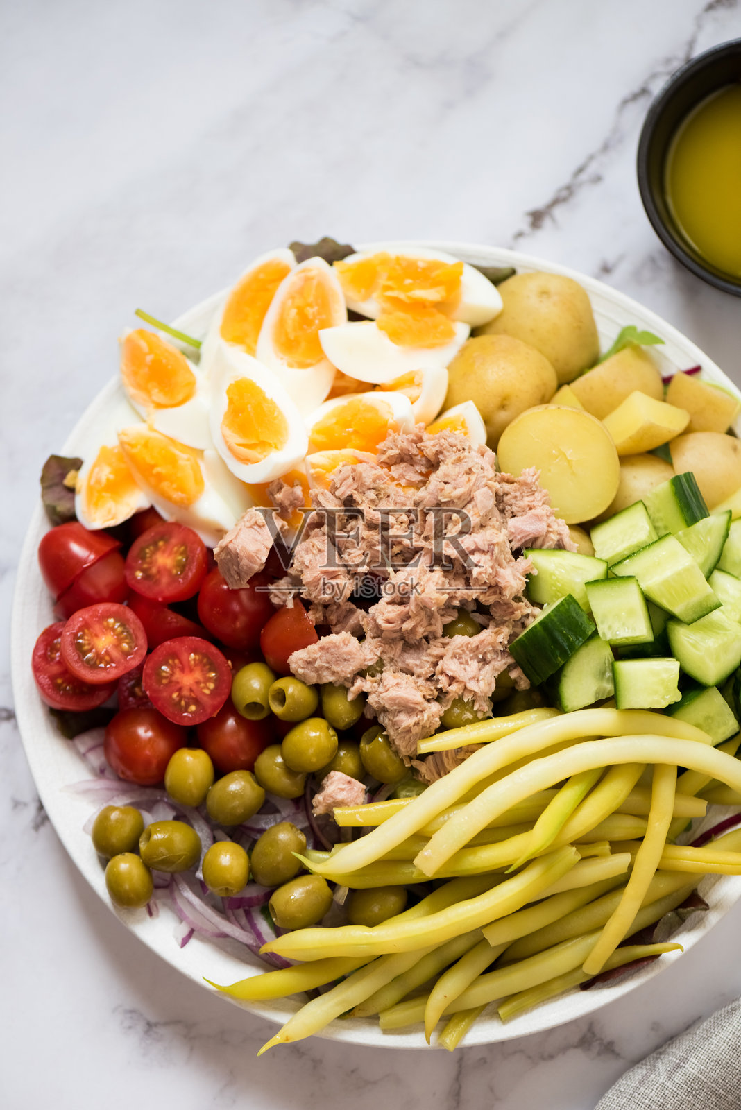 尼斯沙拉 - 法式沙拉，配有鸡蛋、金枪鱼、西红柿、绿橄榄、土豆、青豆和黄瓜照片摄影图片