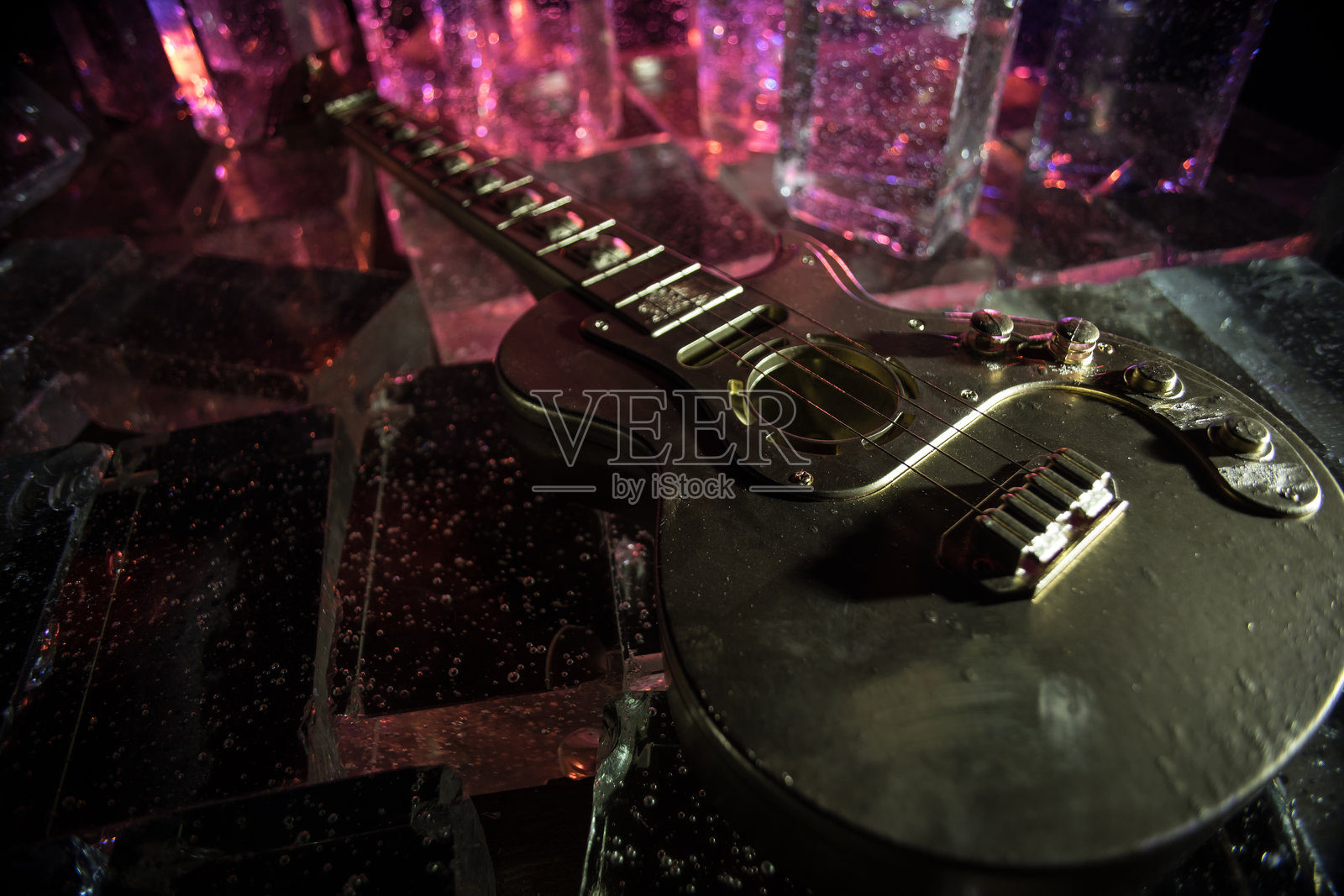 音乐概念：黑色背景下的吉他微缩模型，配有生动的光线、烟雾和火焰效果。金色电吉他在戏剧性的聚光灯下。照片摄影图片