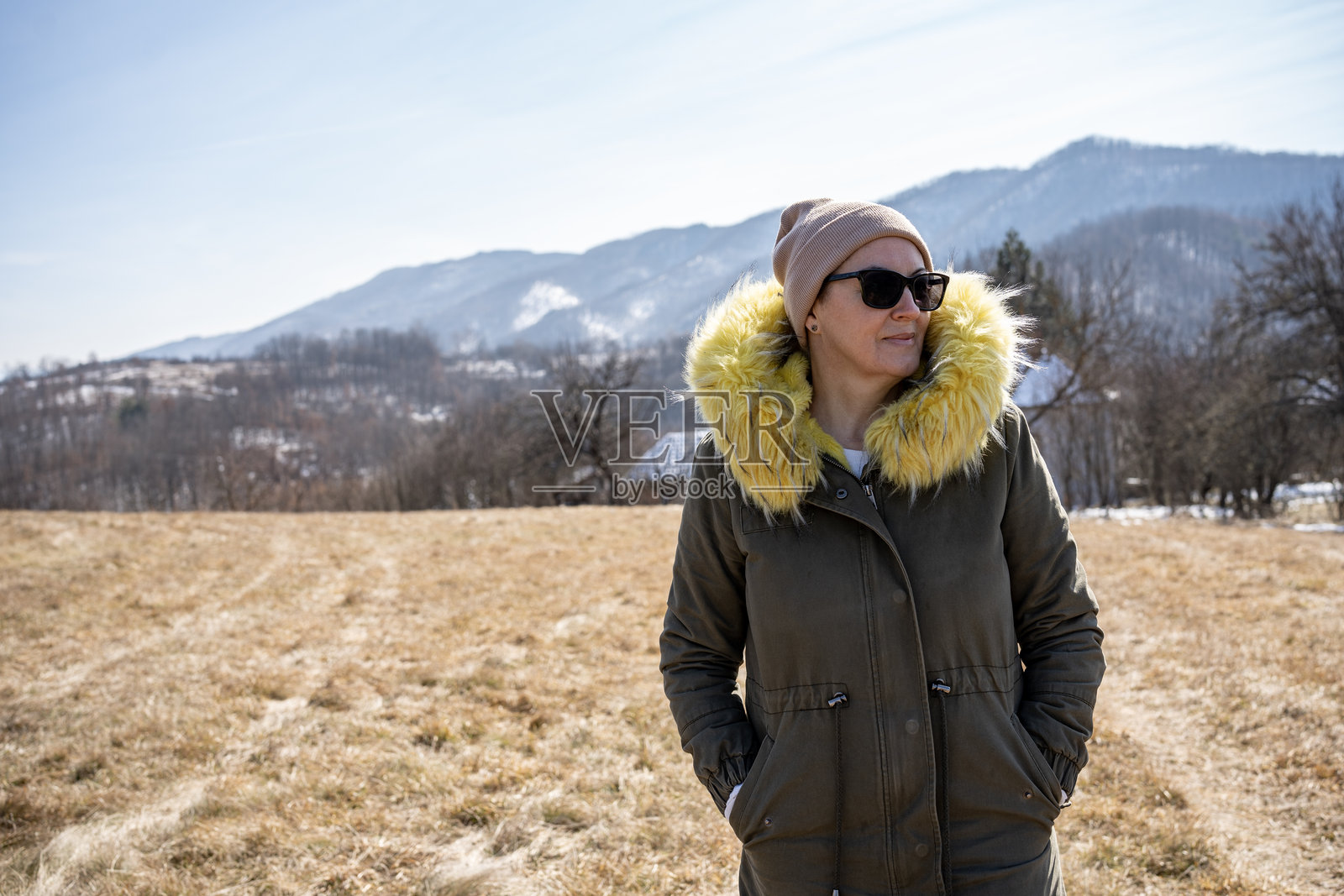 穿着温暖衣物的女性在冬季的风景乡村中站立照片摄影图片