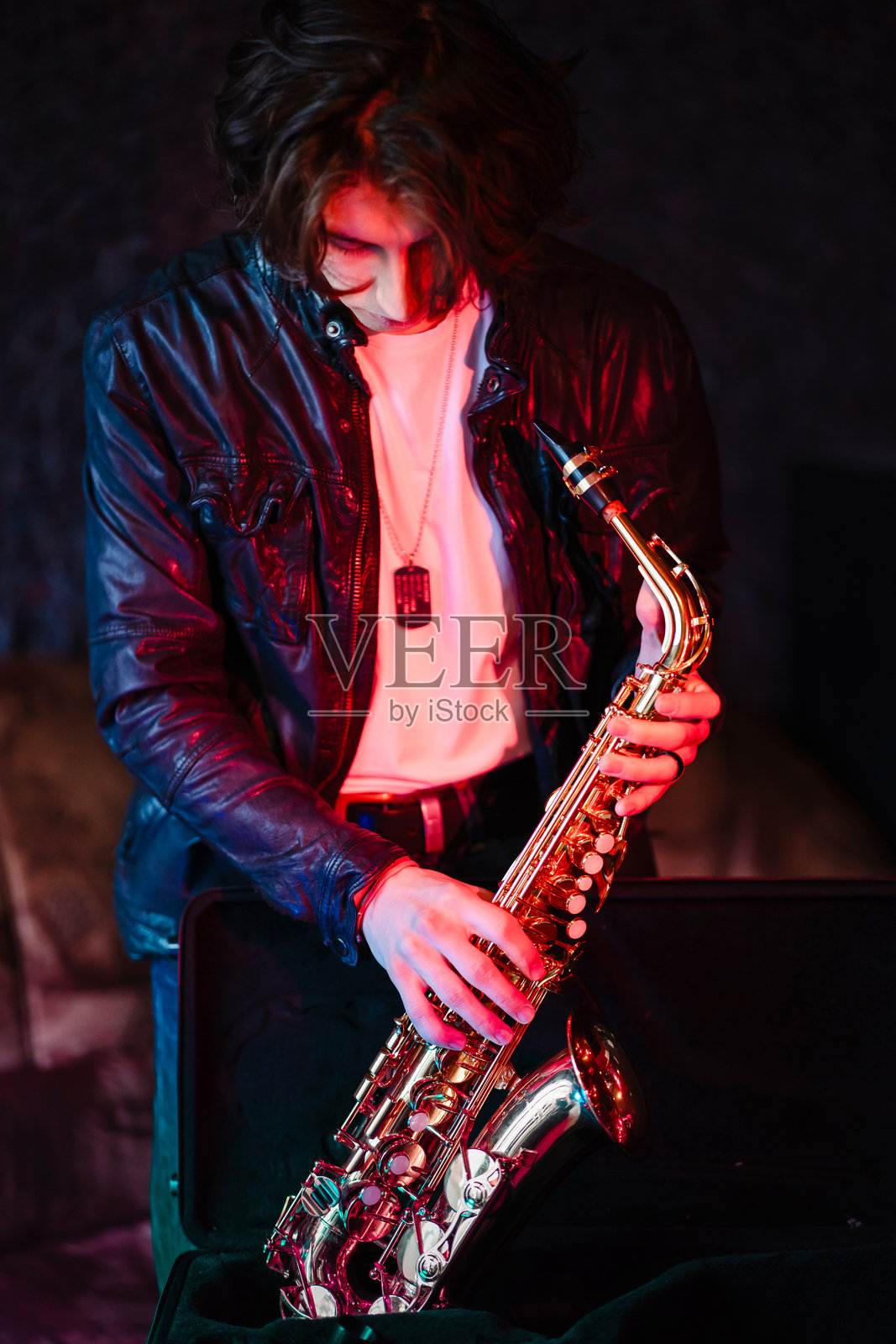 年轻的萨克斯演奏者在即兴演奏前准备他的萨克斯风照片摄影图片