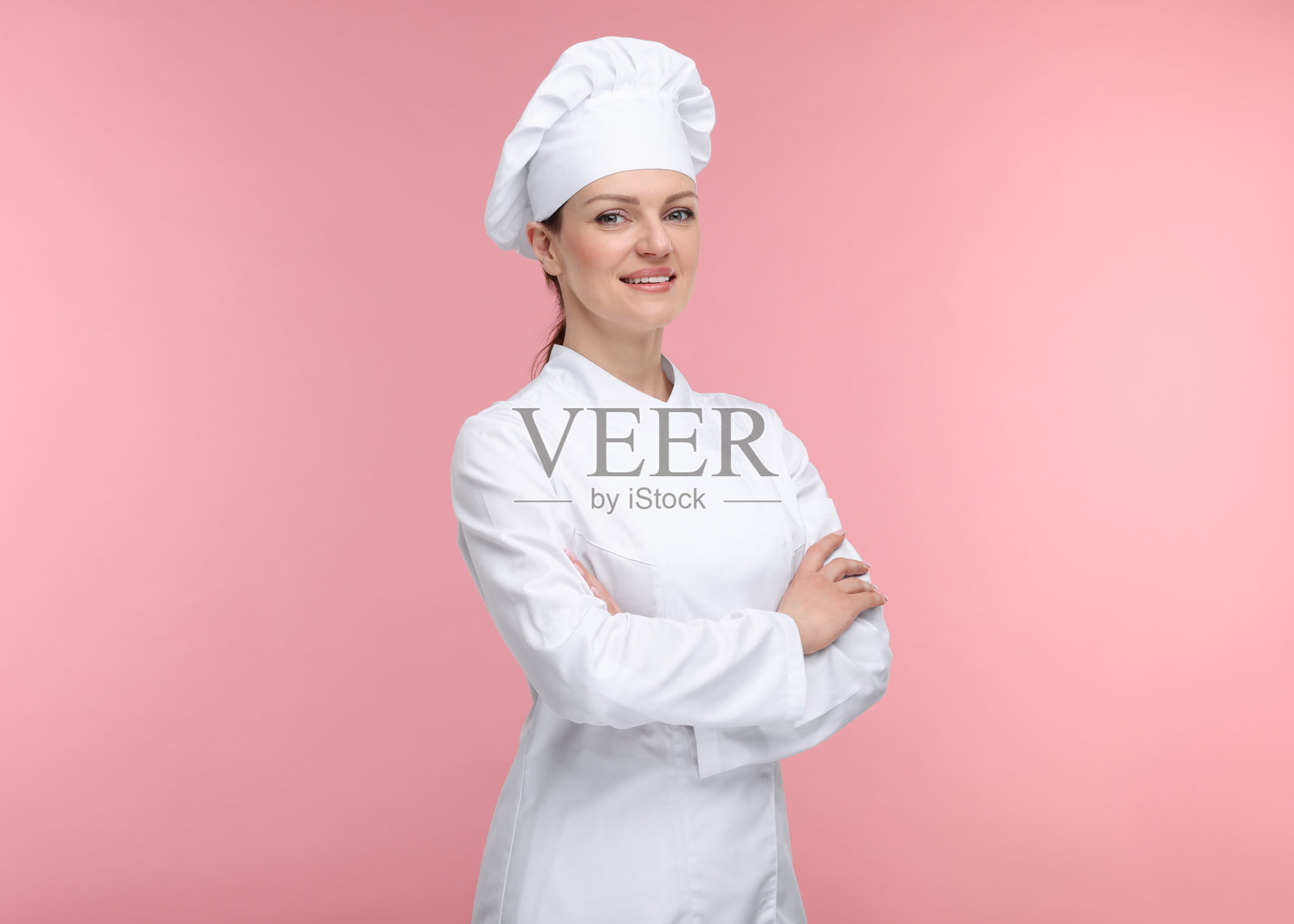 穿着制服的快乐女厨师在粉色背景上照片摄影图片