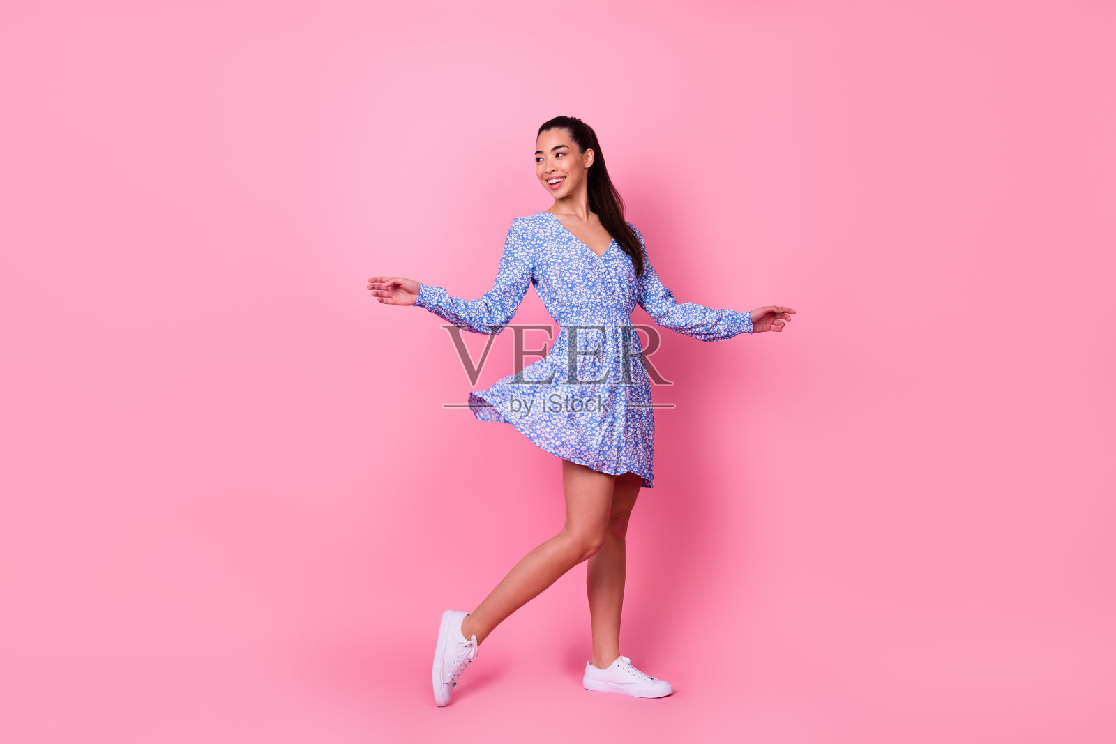 年轻女孩在粉色背景下笑着，回头看，心情愉快，身后空无一人。照片摄影图片