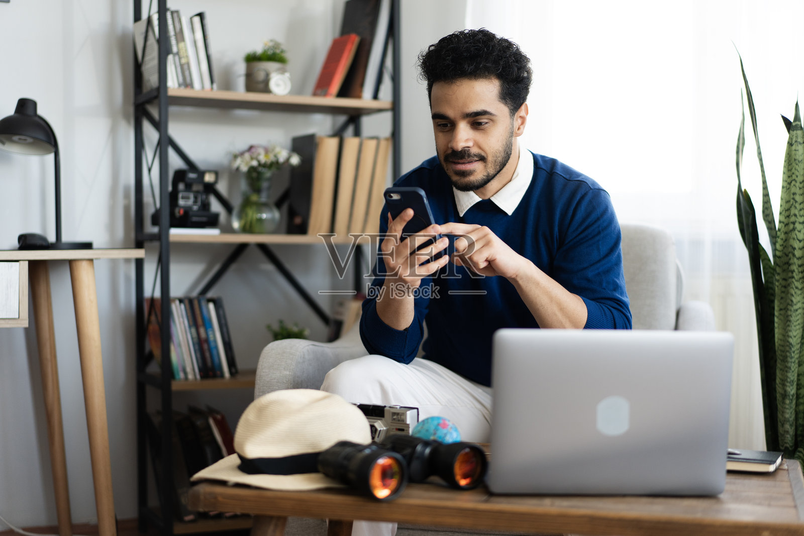 年轻男子正在使用智能手机和笔记本电脑规划他的下一次旅行照片摄影图片