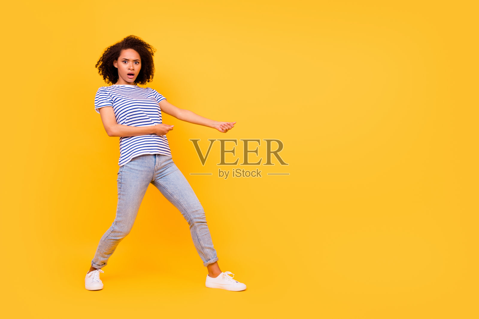 全身侧面肖像，惊讶的人双臂拉着空中绳索，背景为黄色。照片摄影图片