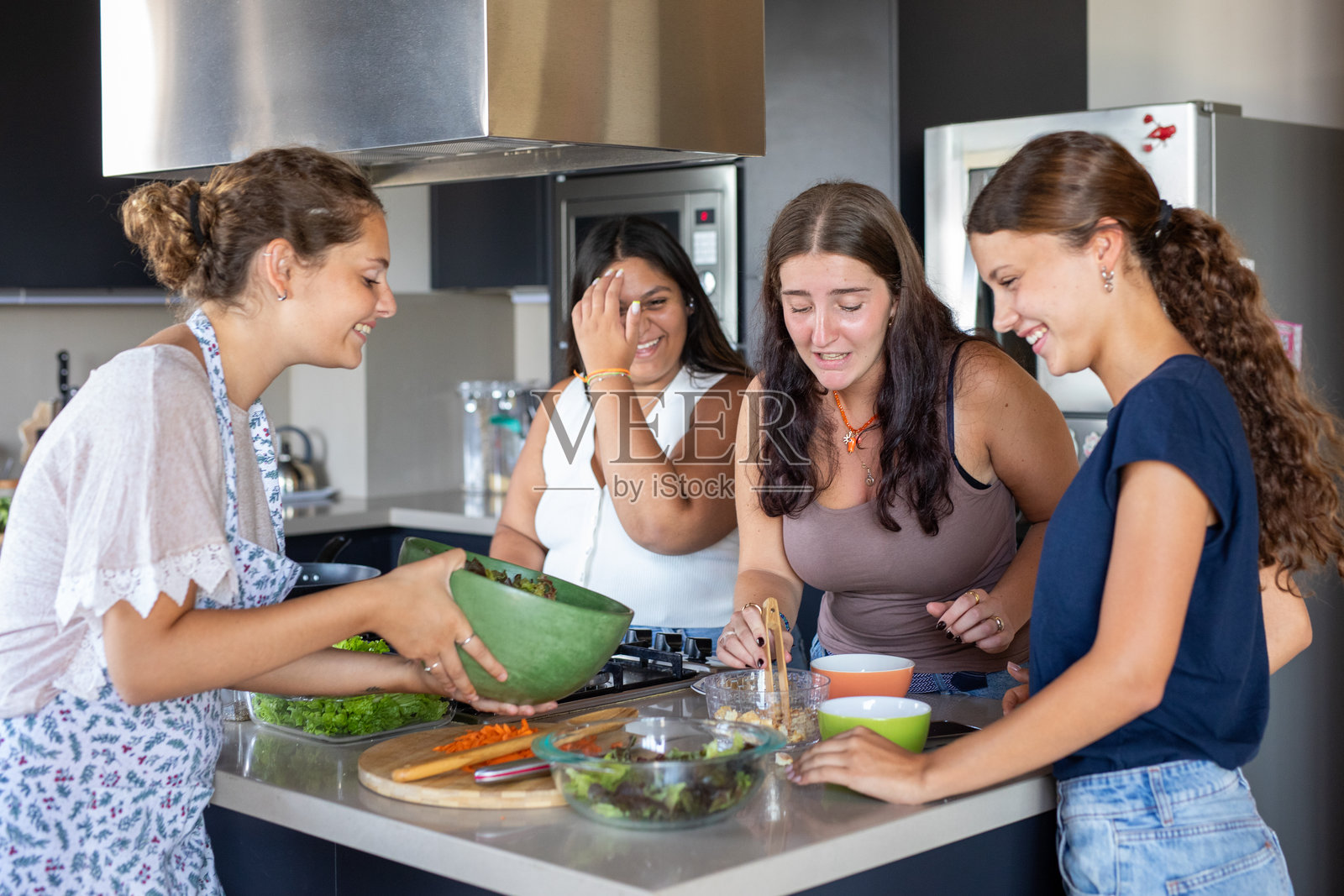 快乐的年轻女性朋友们在厨房里准备沙拉照片摄影图片