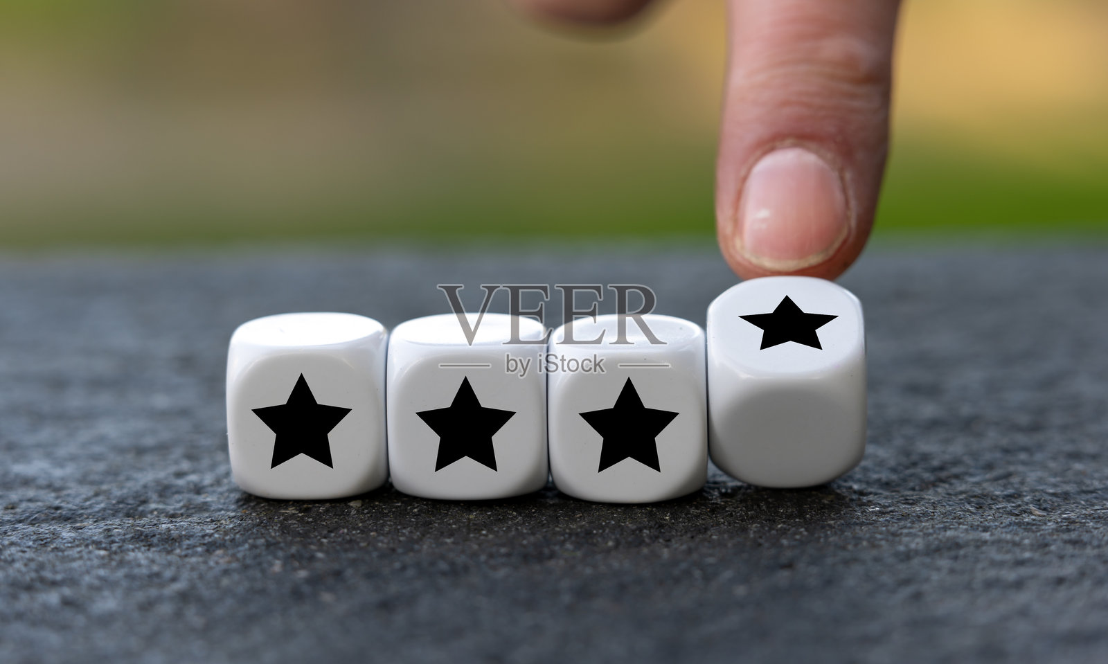 手转动立方体，将星星的数量从三颗变为四颗。四星评级的符号。照片摄影图片