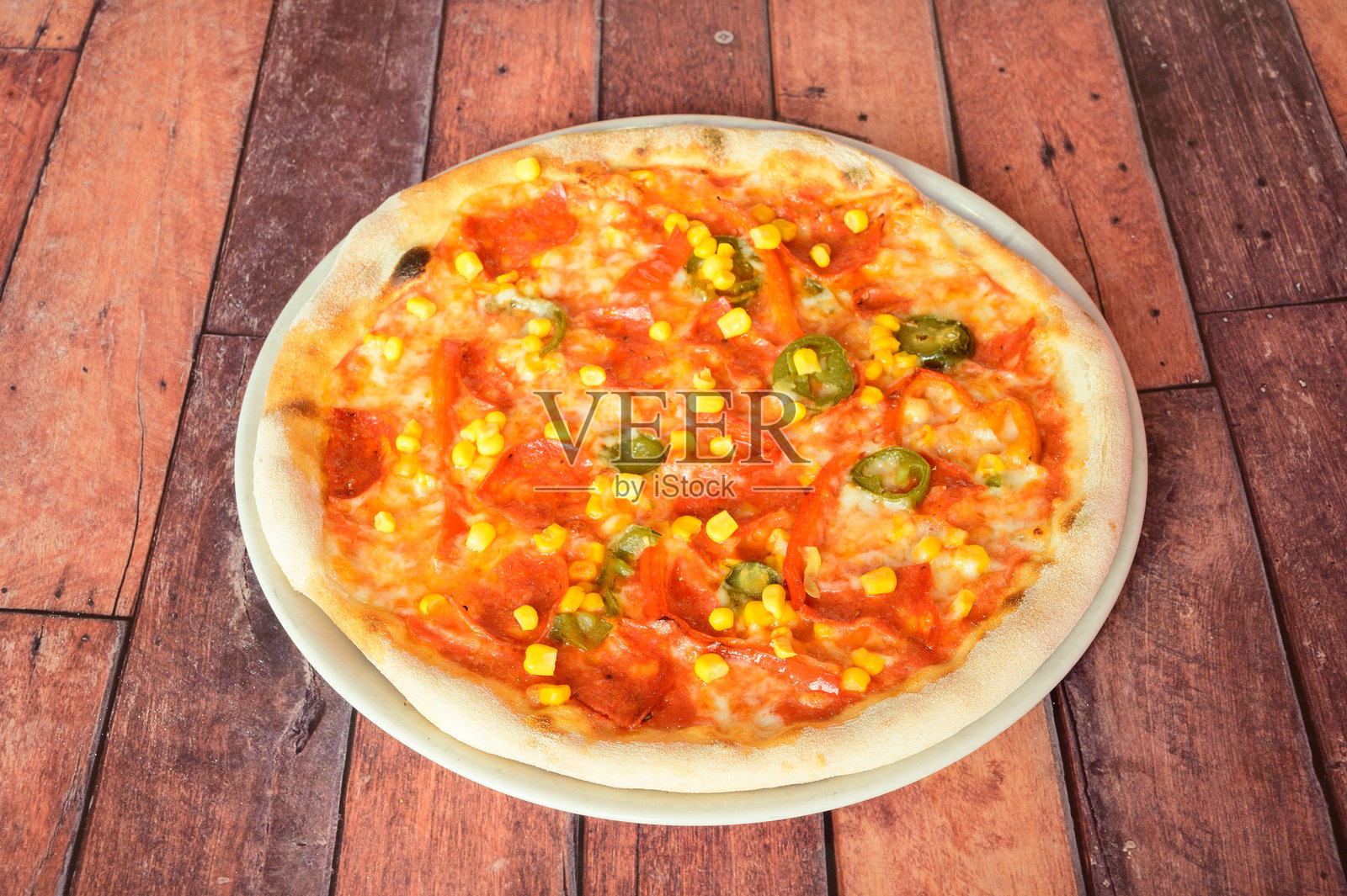 一块上面放有玉米和辣椒的披萨照片摄影图片