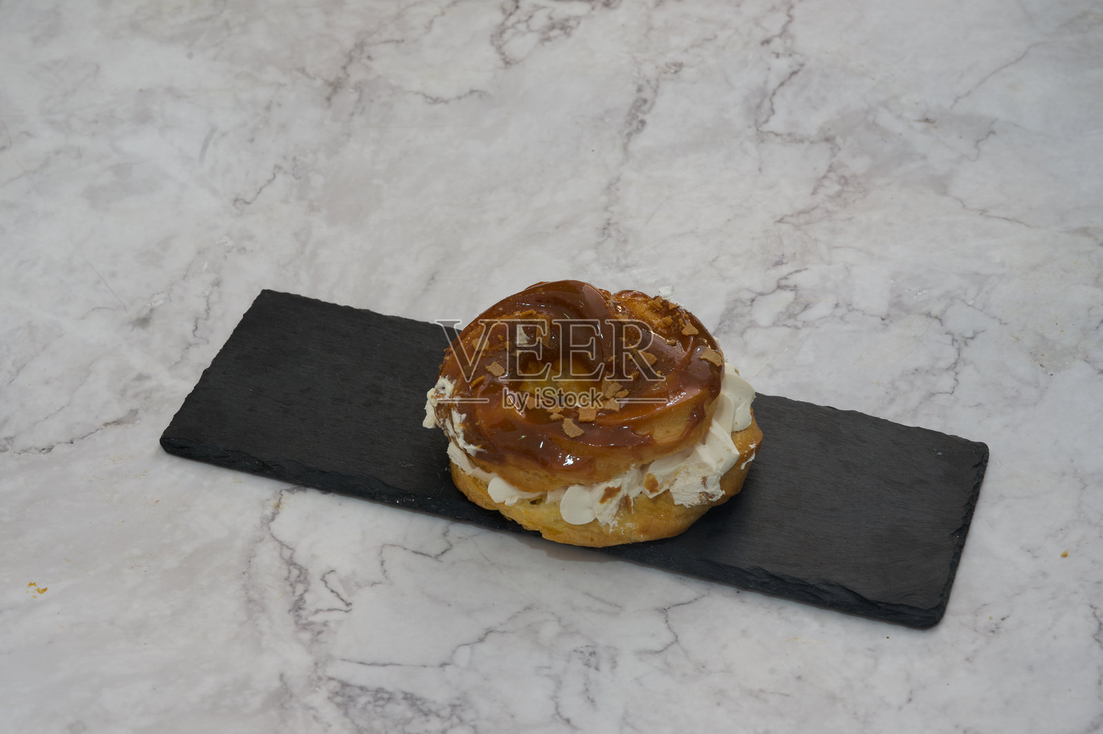 一个夹心奶油的甜甜圈放在黑色盘子上照片摄影图片