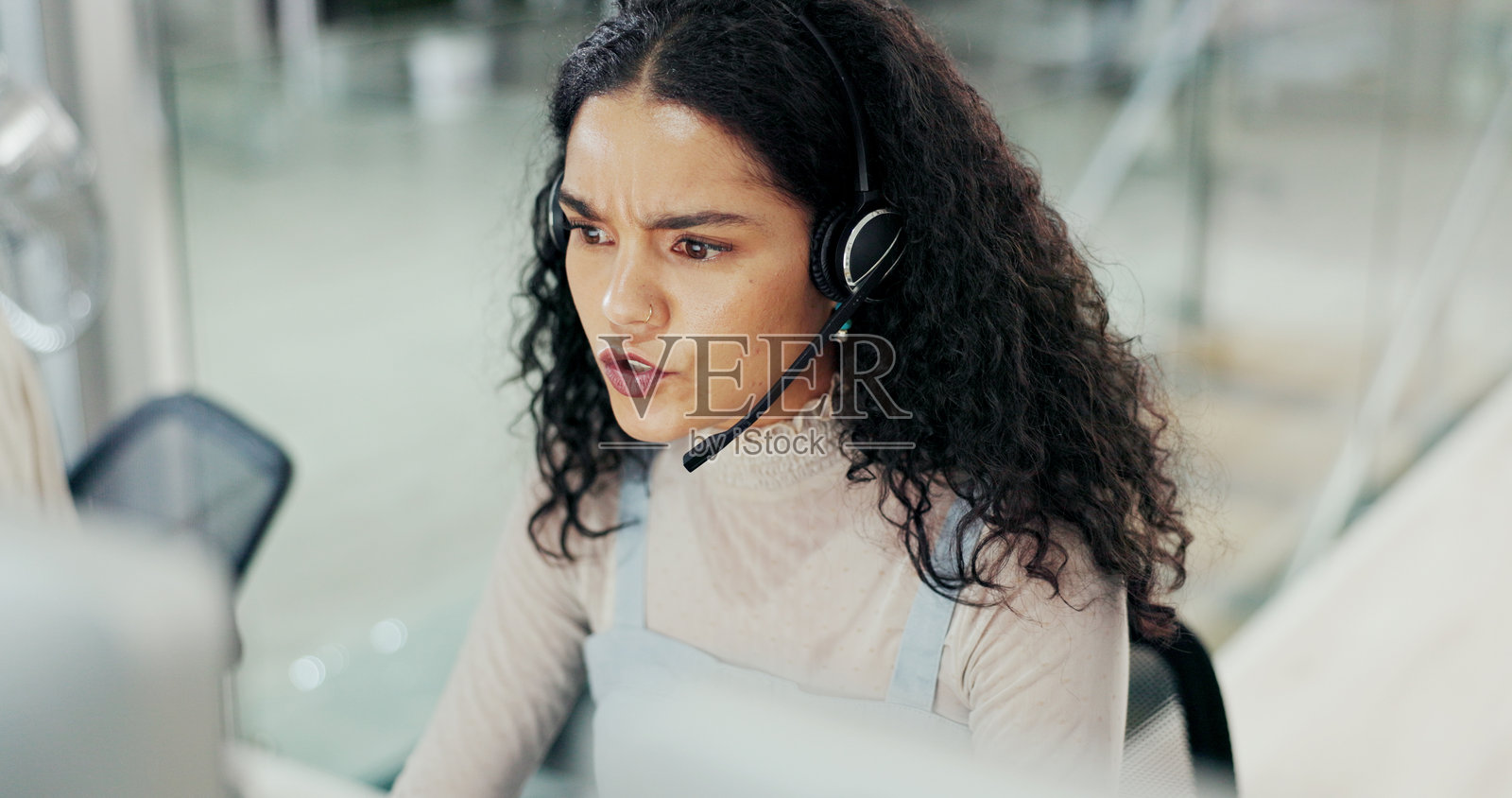 困惑的女性在客服中心佩戴耳机通话，解决问题和客户关系管理的压力。上方，顾问与客户讨论技术支持、电话营销和常见问题解答的建议。照片摄影图片