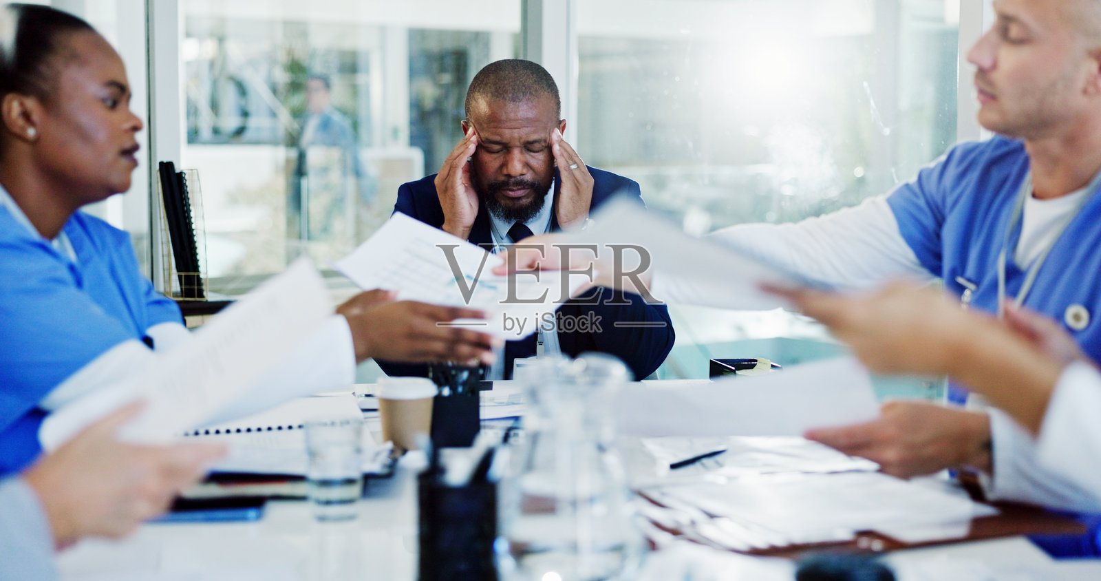 感到沮丧的男人，医生或因文件而头痛，在医院的会议中因过度工作而感到压力或焦虑。商人、董事会成员或因偏头痛而疲惫，面临诊所混乱或医疗资金不足的问题。照片摄影图片