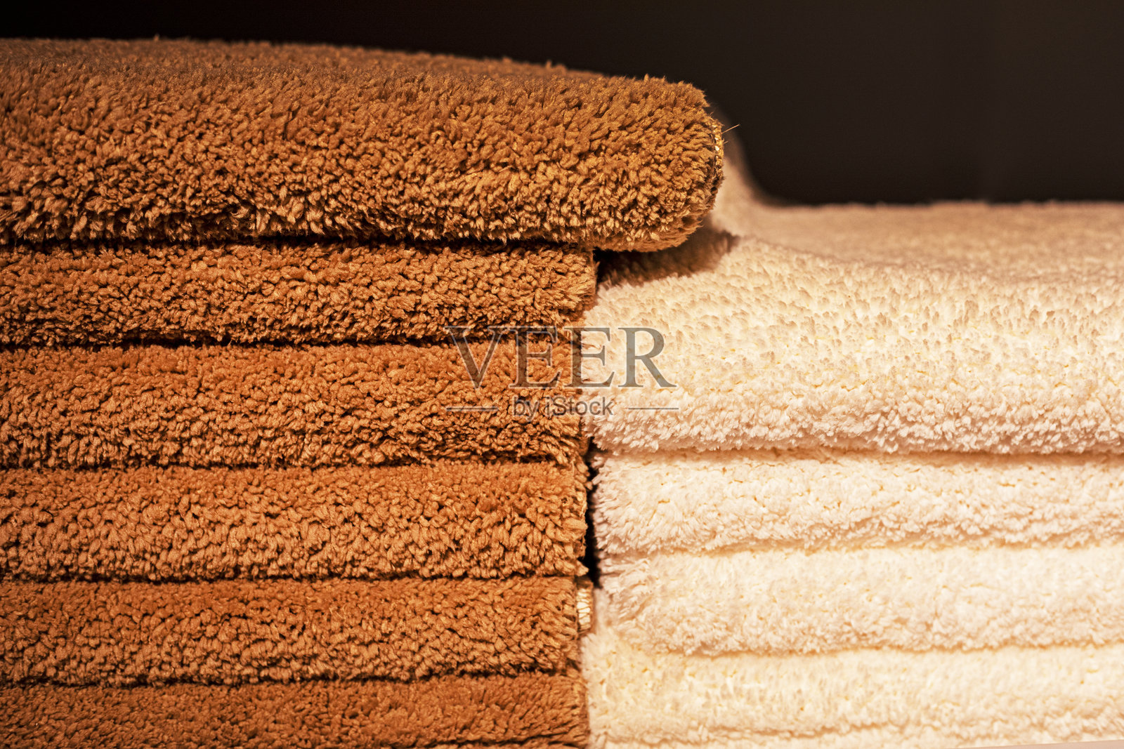 浅米色和深棕色的毛巾叠放成堆。照片摄影图片