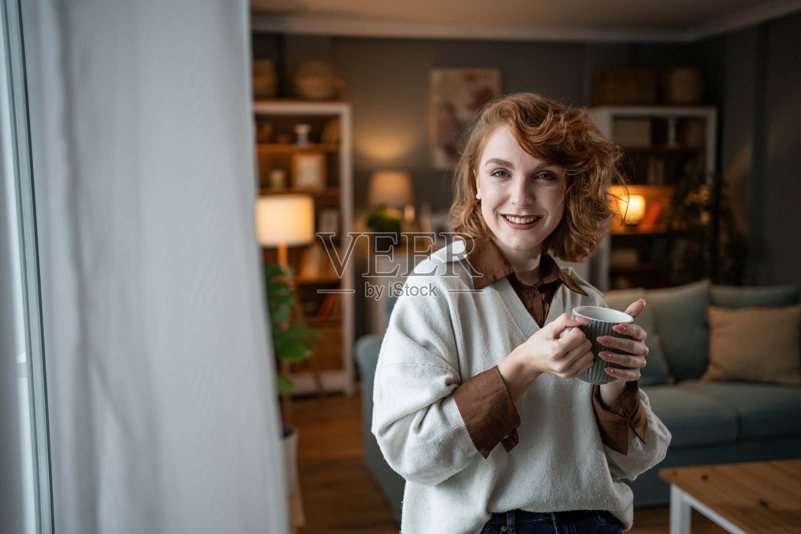 年轻女性在客厅微笑着拿着一个杯子照片摄影图片