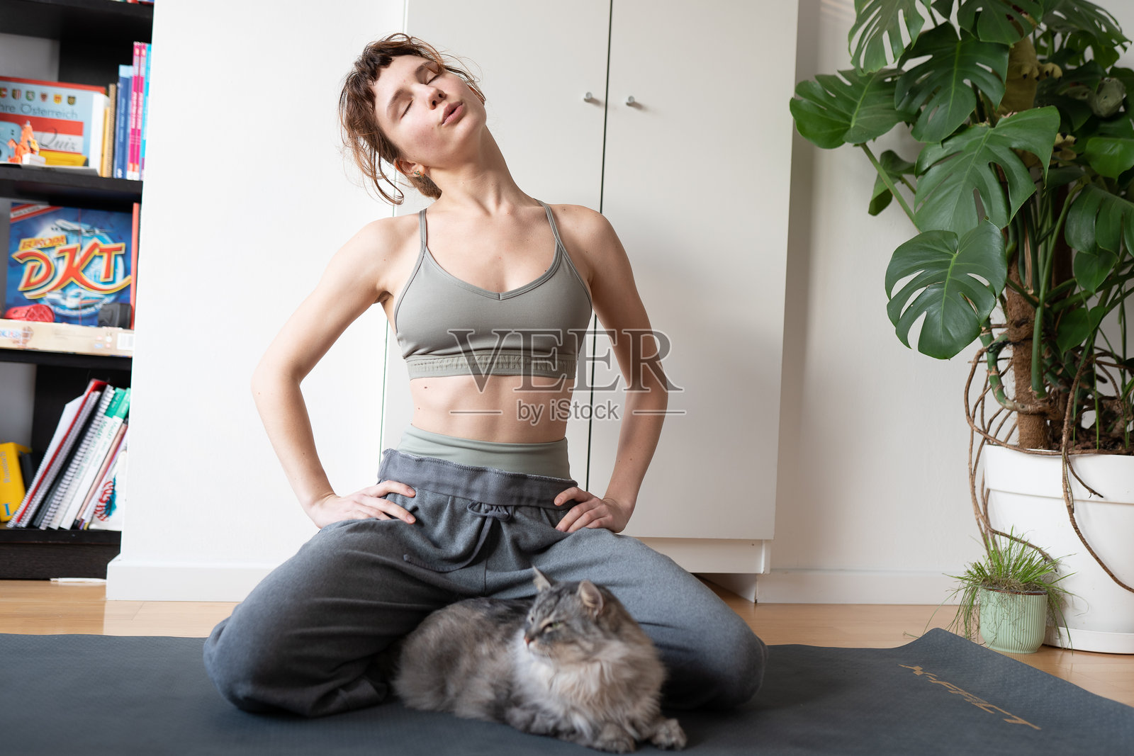 年轻女性与她的宠物猫一起做瑜伽照片摄影图片