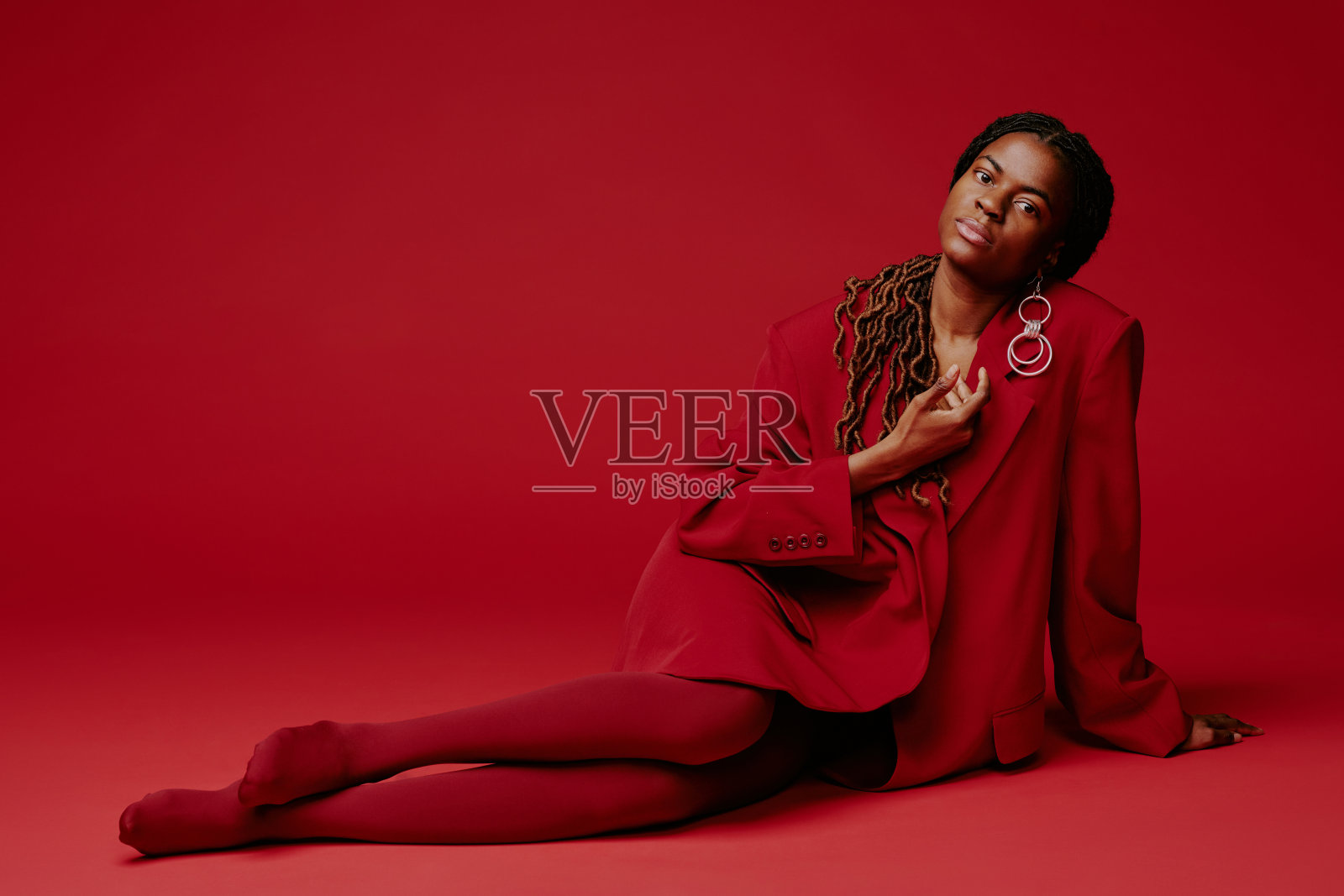 在红色背景前摆姿势，穿着时尚的红色服装照片摄影图片