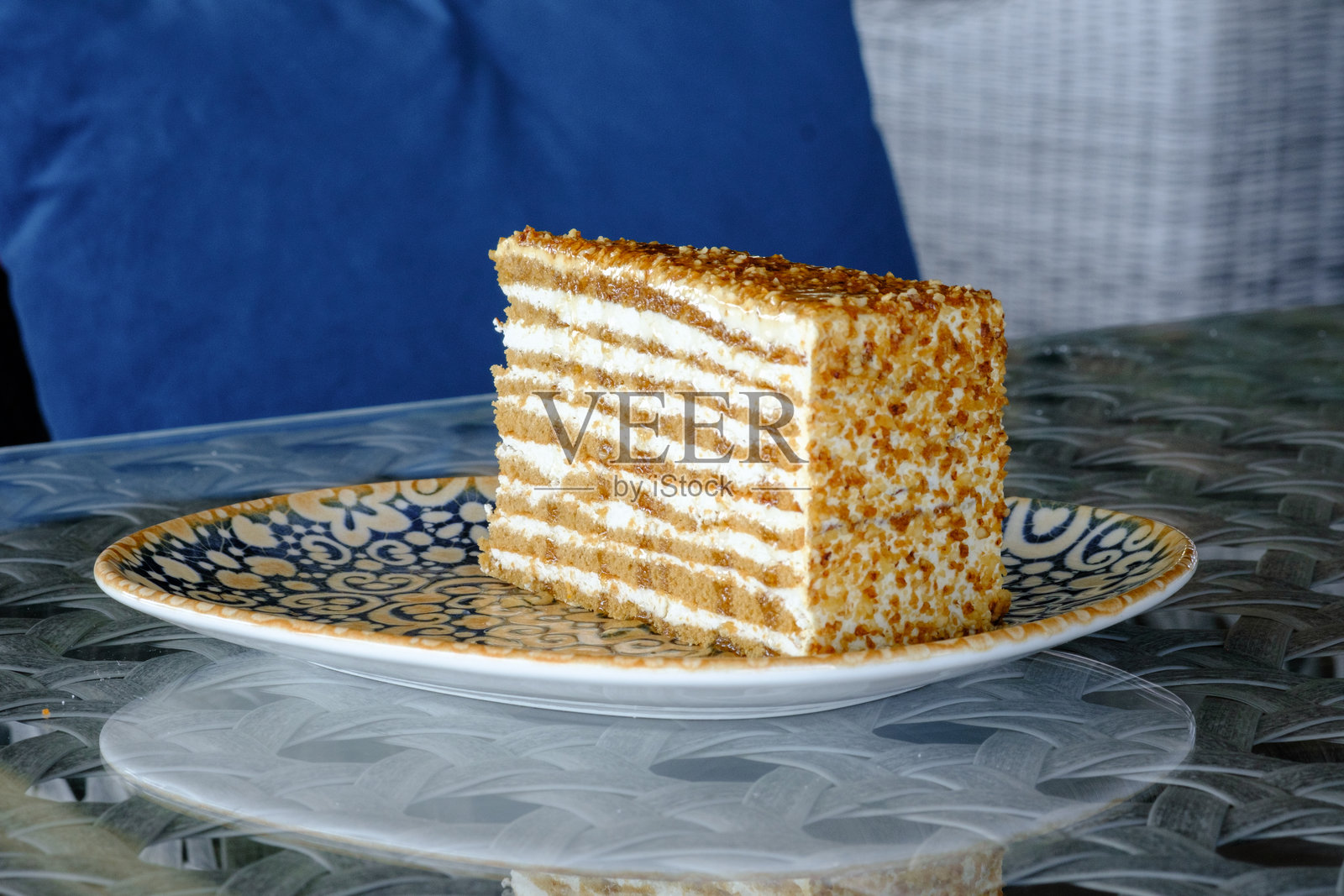 一片层次分明的蛋糕，上面撒有脆脆的配料，放在一个精美的盘子上照片摄影图片