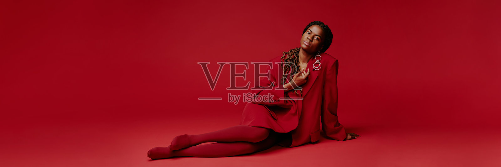 坐着的女性穿着时尚的红色服装，自信地摆姿势照片摄影图片