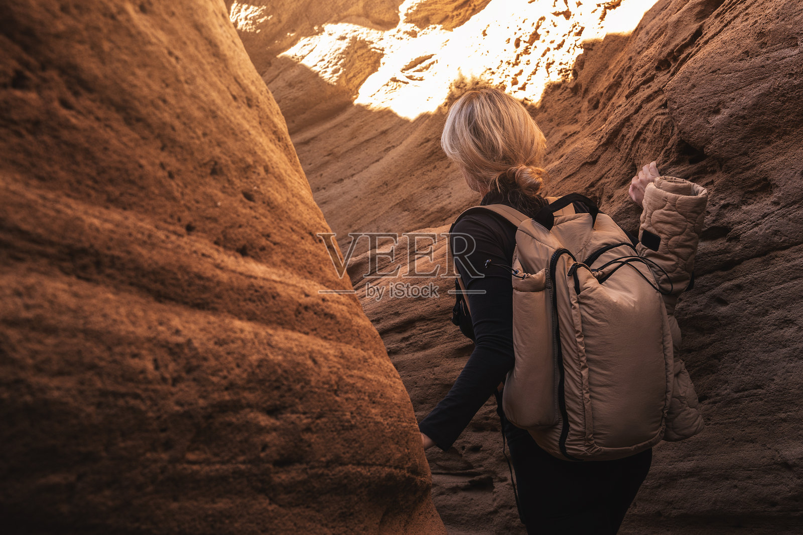 女性徒步旅行者在狭窄的砂岩峡谷中探险，背着户外装备的背包照片摄影图片