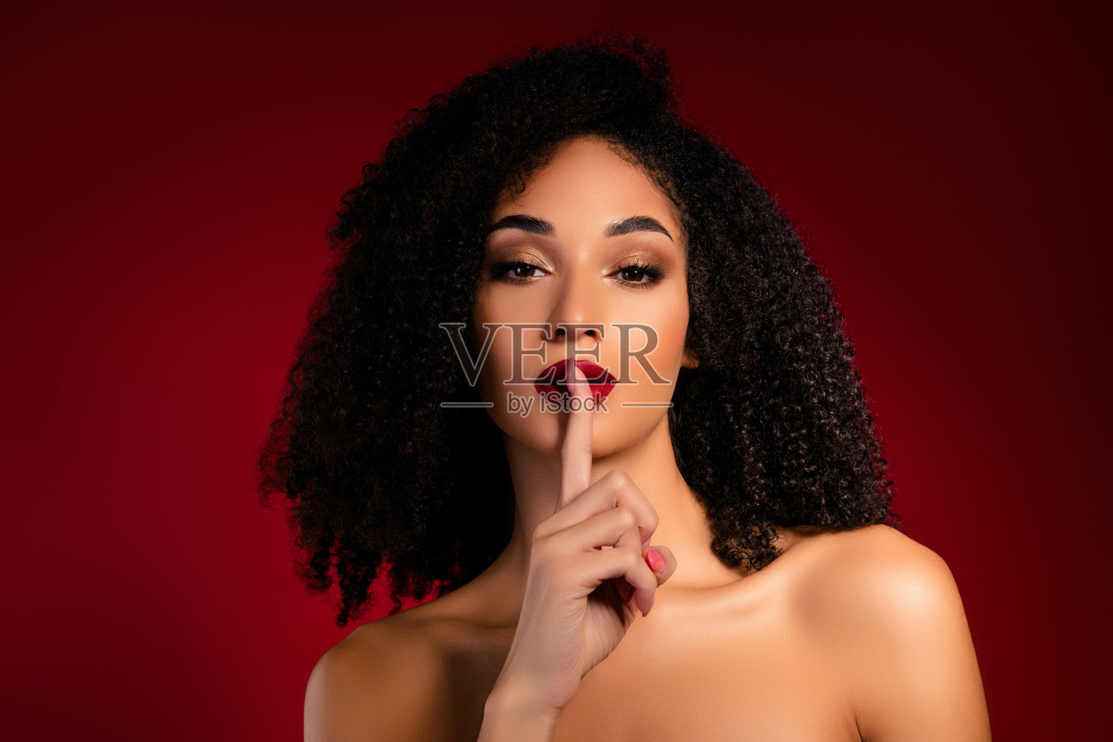 时尚富有的女孩用手指放在嘴唇上示意安静，妆容鲜艳。照片摄影图片